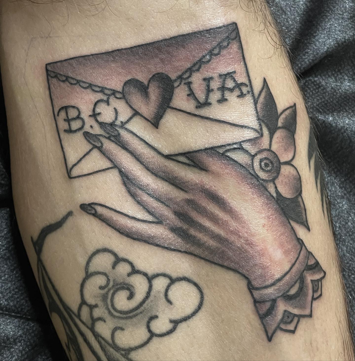 Hand holding envelope American traditional tattoo on the forearm by Bryan Humphries
