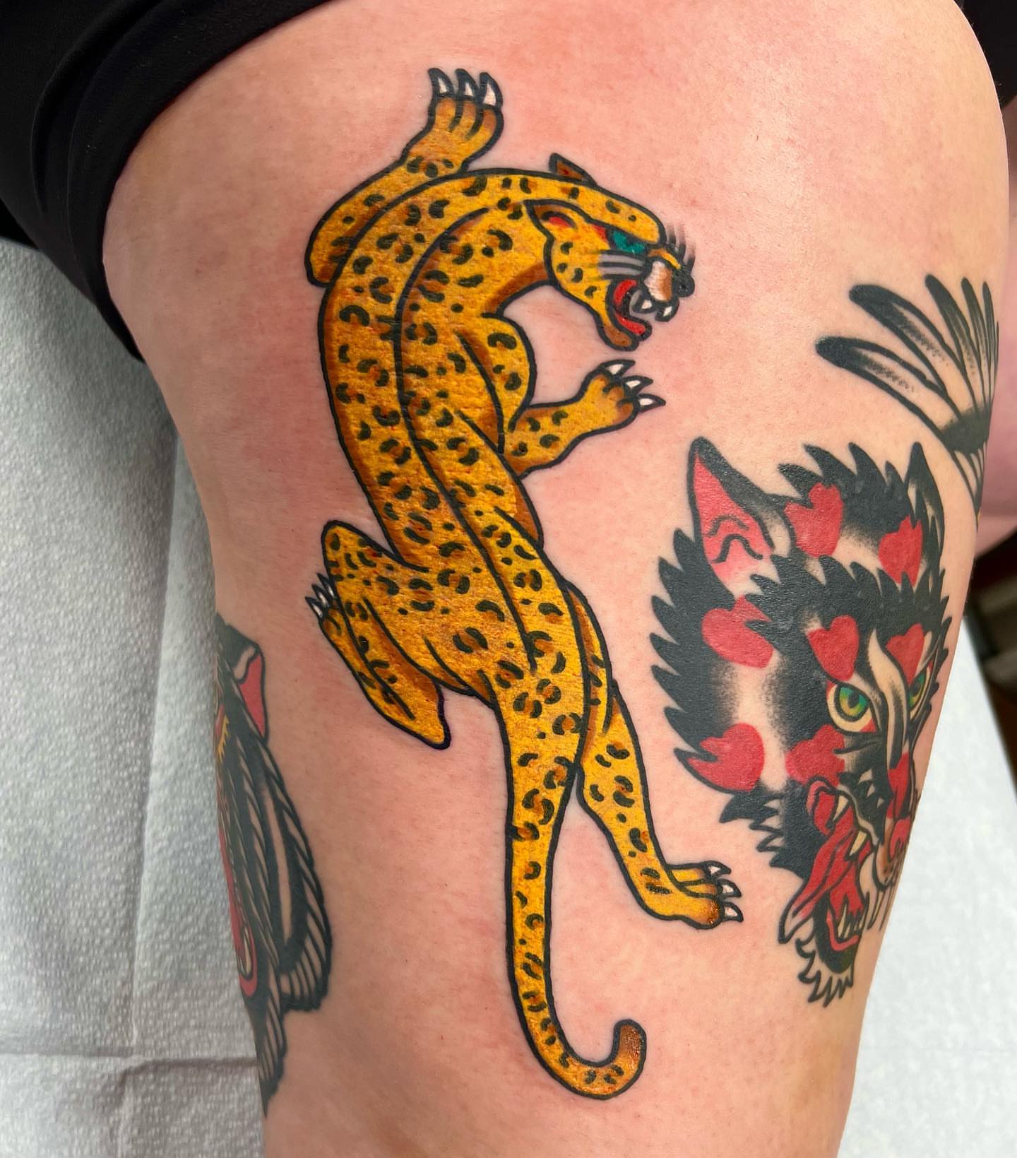Leopard and wolf American traditional tattoo on the thigh by Nicholas Mella, Nashville, Tennessee