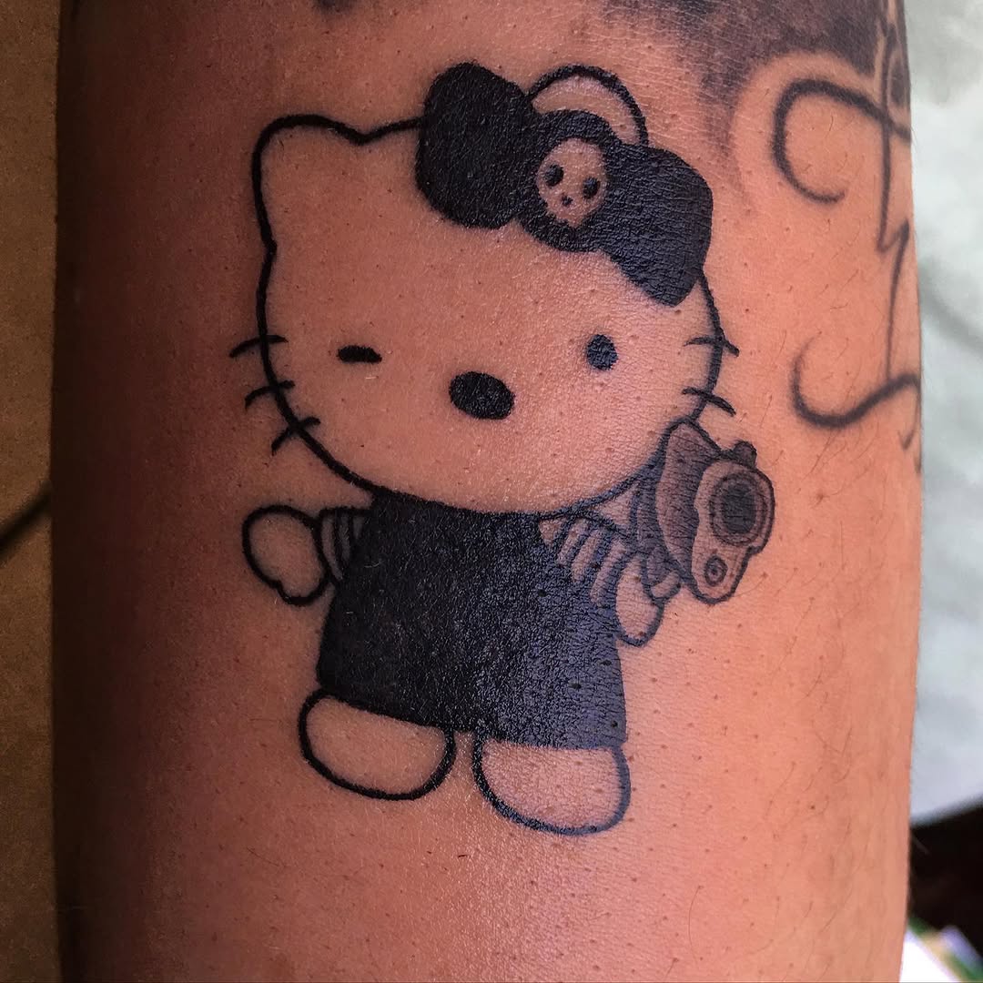 Hello Kitty with a gun new school tattoo on the forearm by Ramirez Tattooing