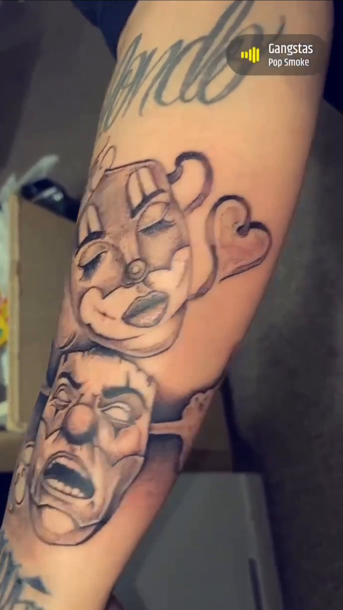 Comedy and tragedy masks with lettering realism tattoo on the forearm by Ramirez Tattooing