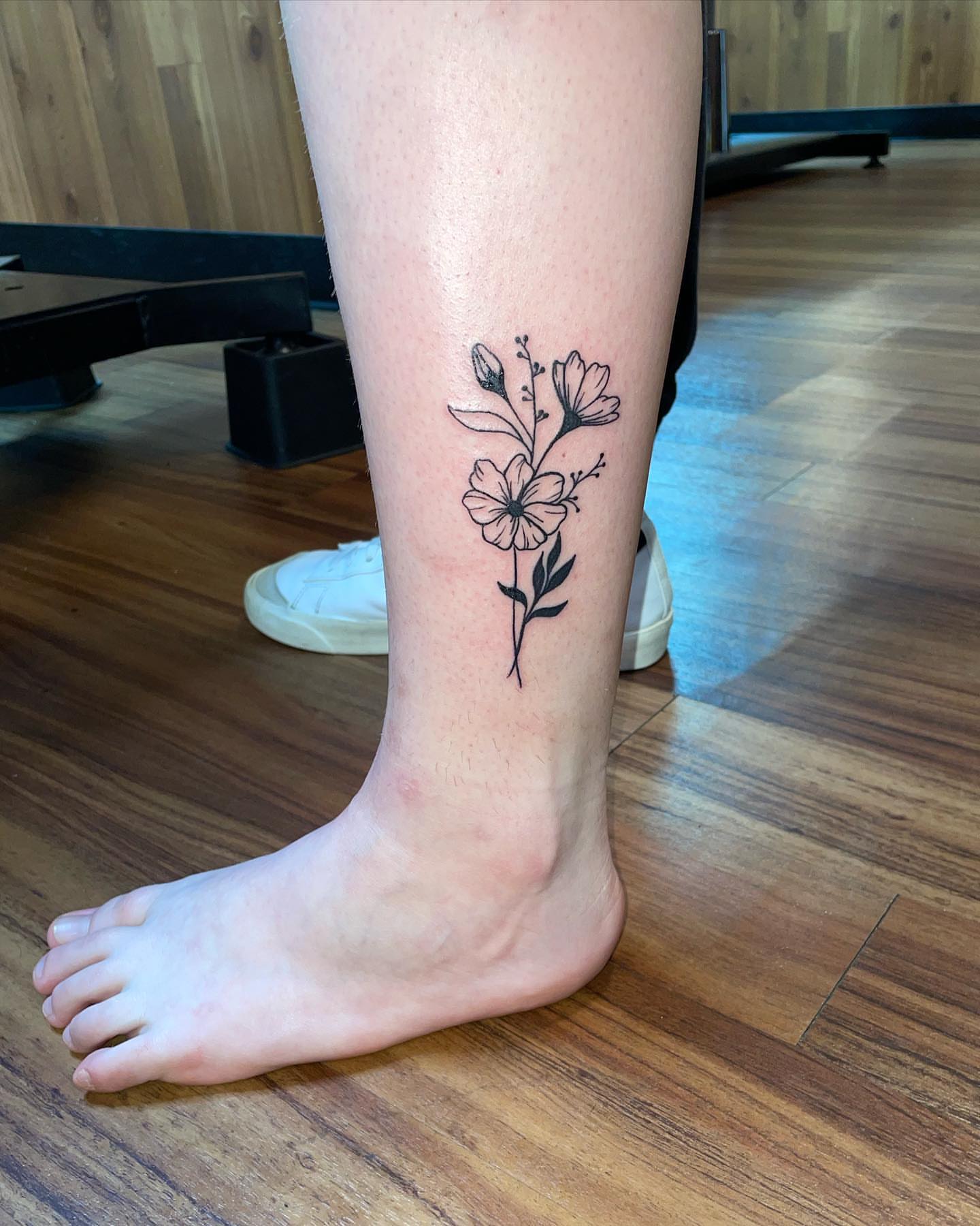 Flower fine line tattoo on the calf by Anna sabrowsky