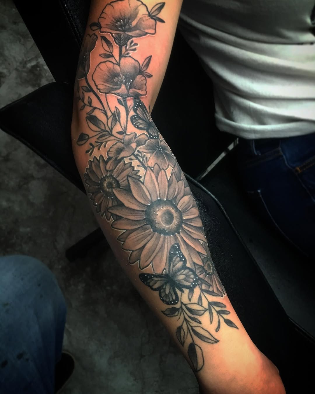 Flowers and butterflies fine line tattoo on the forearm by Cody Wolfe