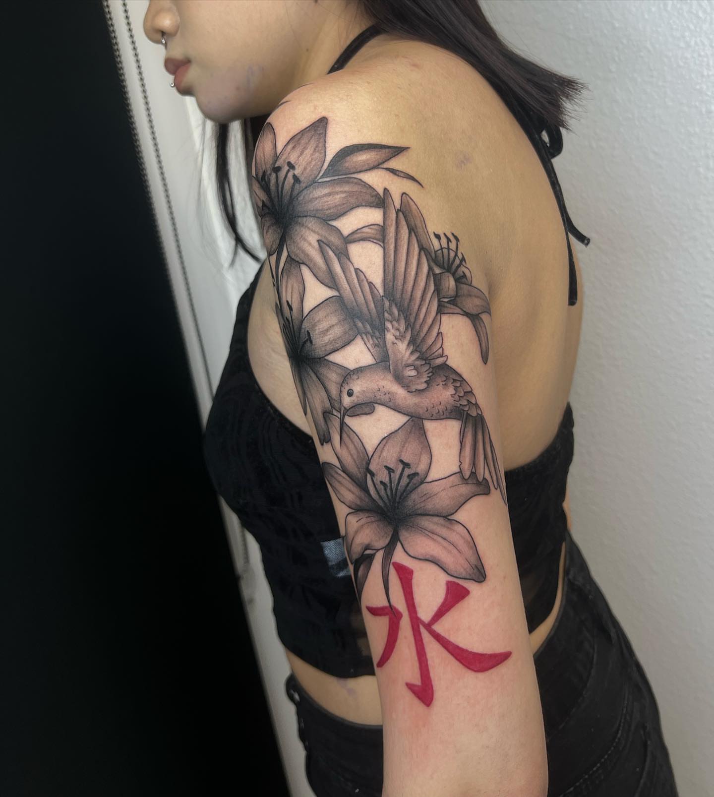 Bird and lilies realism tattoo on the upper arm by Desirae✨