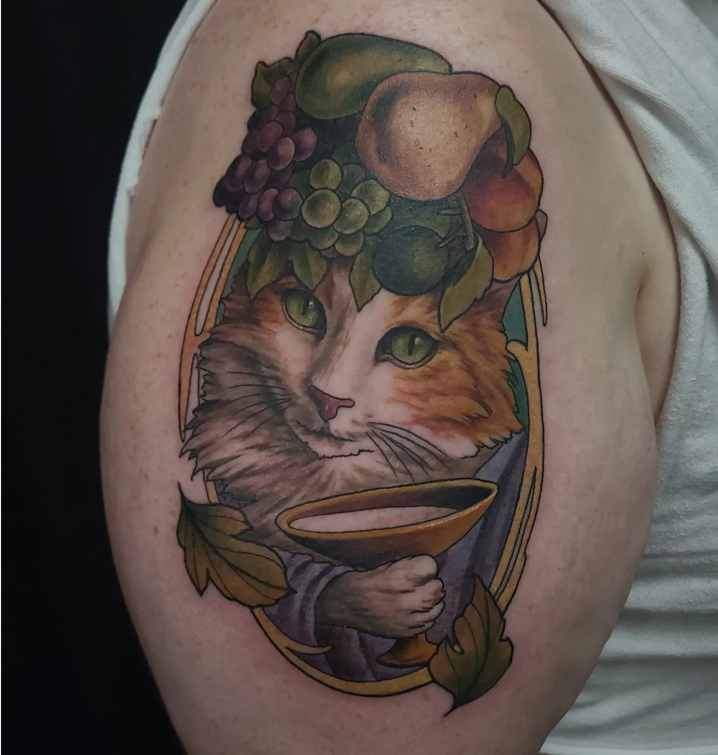 Cat with fruit crown realism tattoo on the upper arm by Gabrielle Nicole Soucie