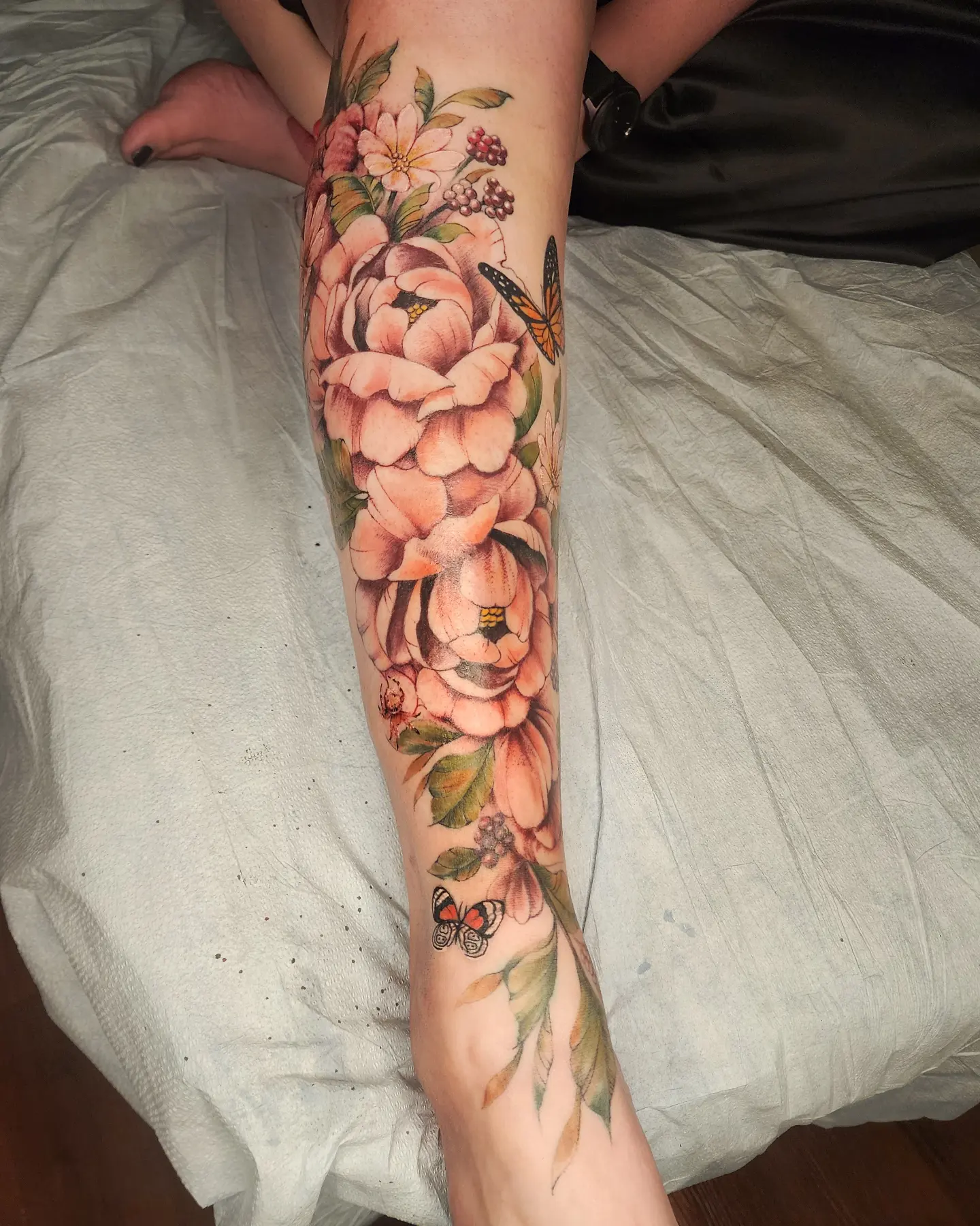 Flowers and butterflies watercolor tattoo on the calf by Neil Ohmie