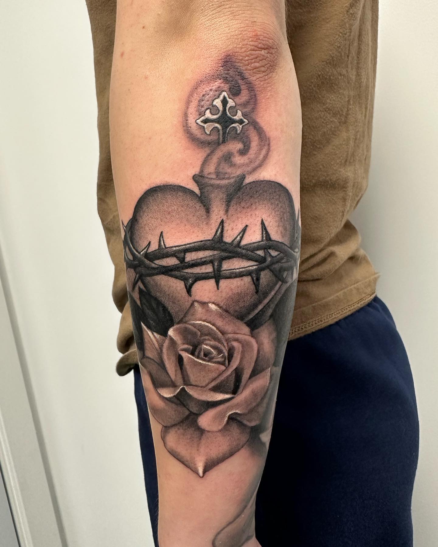 Heart and crown of thorns realism tattoo on the forearm by Junior Nunez