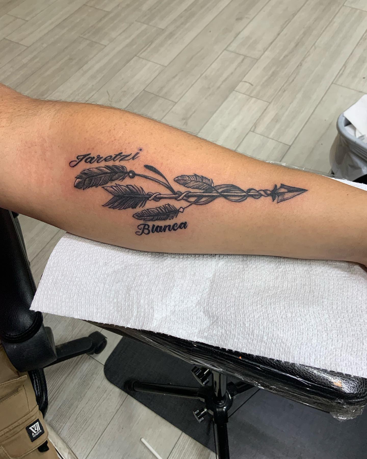 Arrow with feathers black and grey tattoo on the forearm by Daniel Illachek