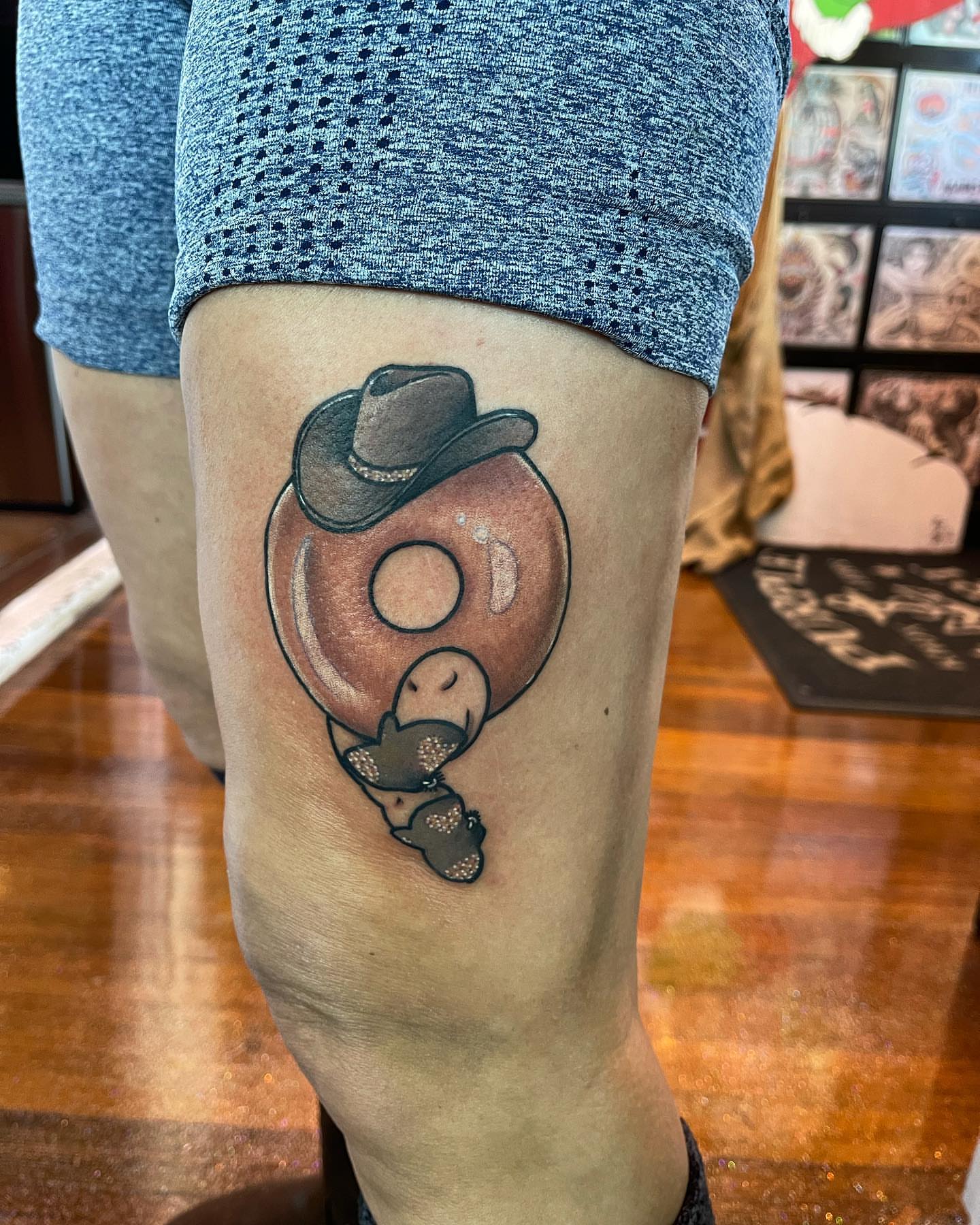 Donut with cowboy hat realism tattoo on the thigh by Erin Miller