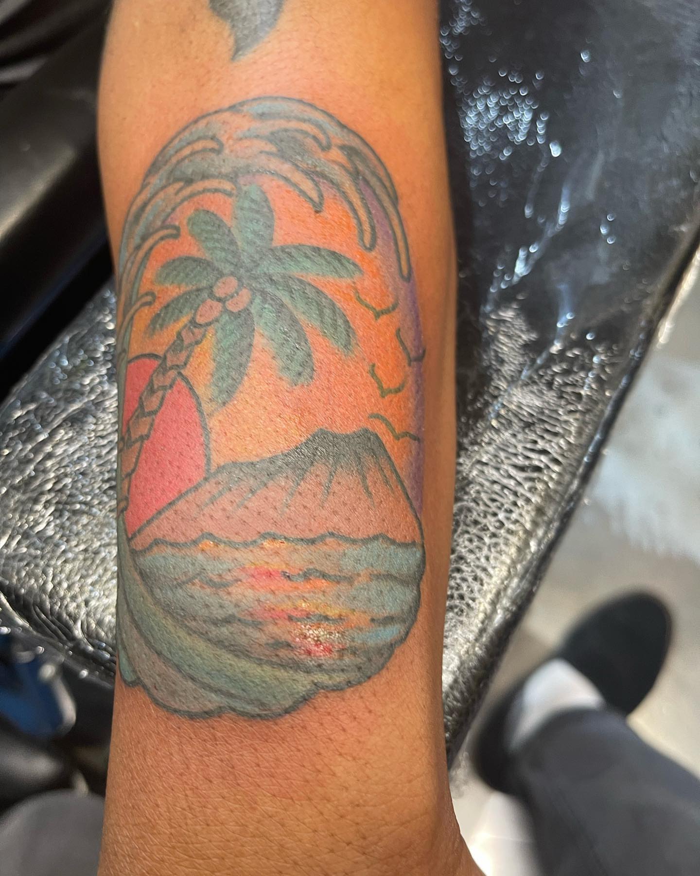 Volcano and palm tree American traditional tattoo on the forearm by Edward Choat