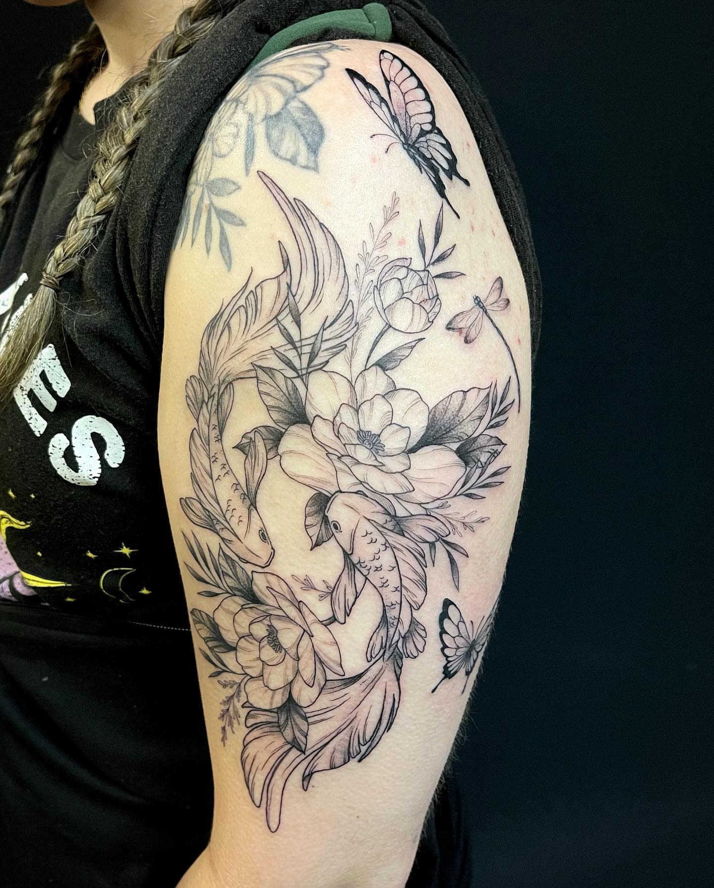 Floral and koi fish realism tattoo on the upper arm by Lexx Christine