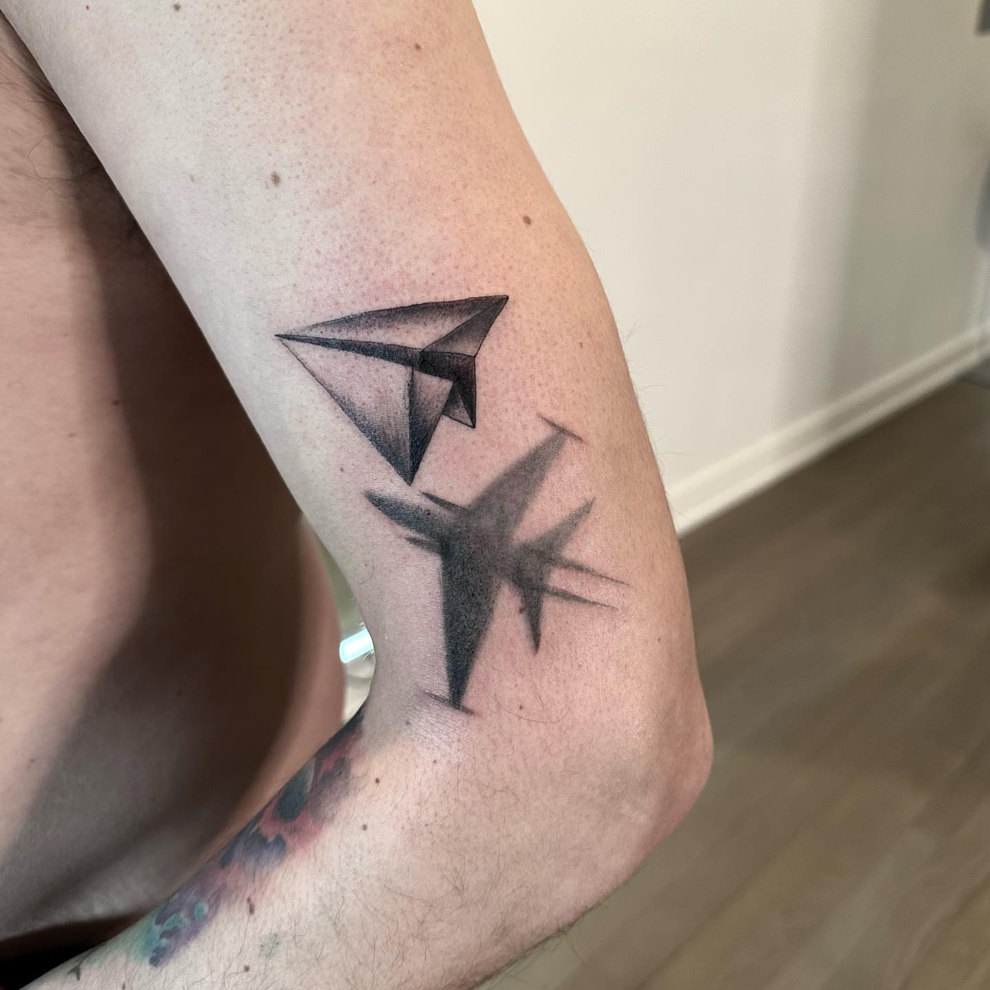 Paper airplane geometric tattoo on the forearm by Matthew Clanin