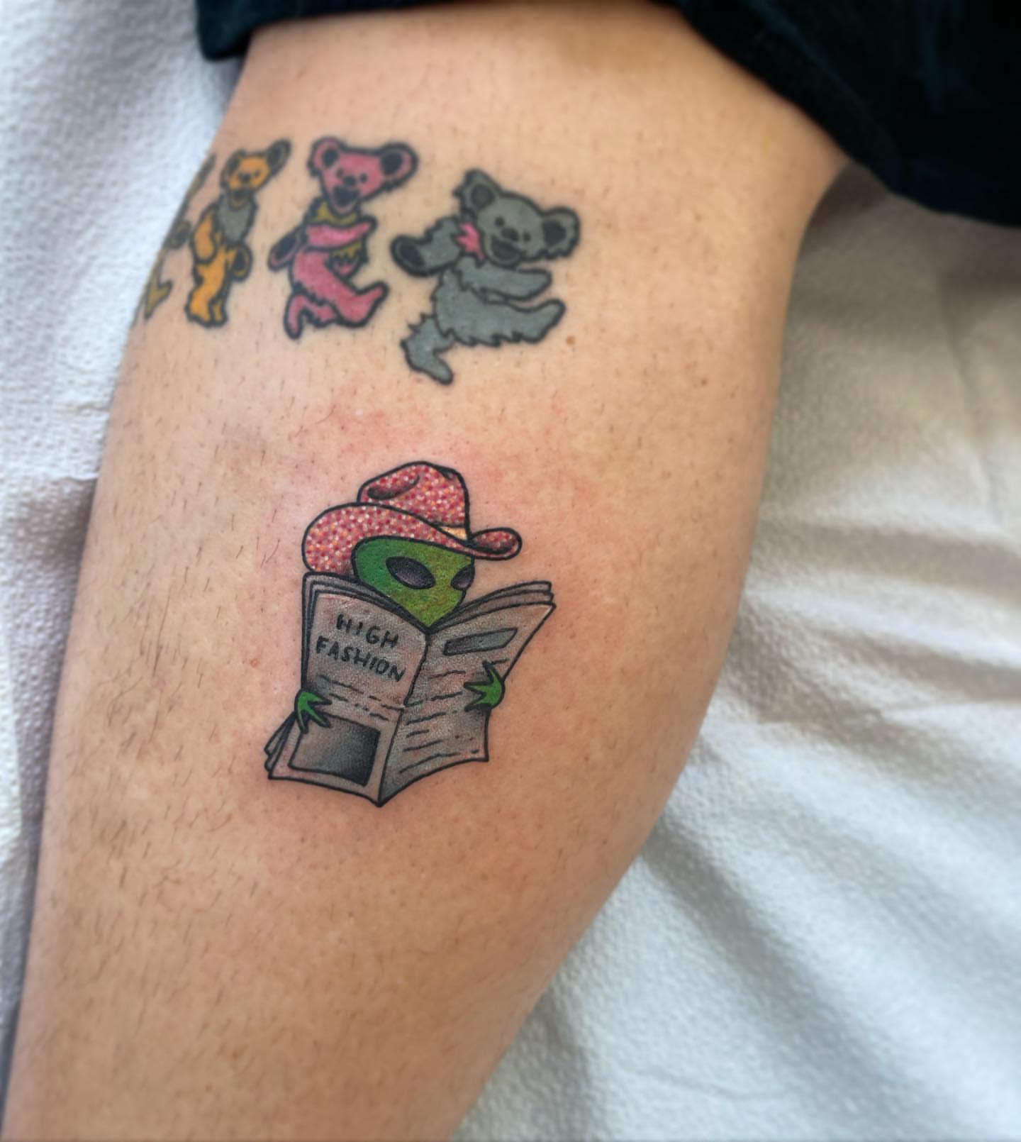 Alien reading newspaper illustrative tattoo on the thigh by Erin Miller