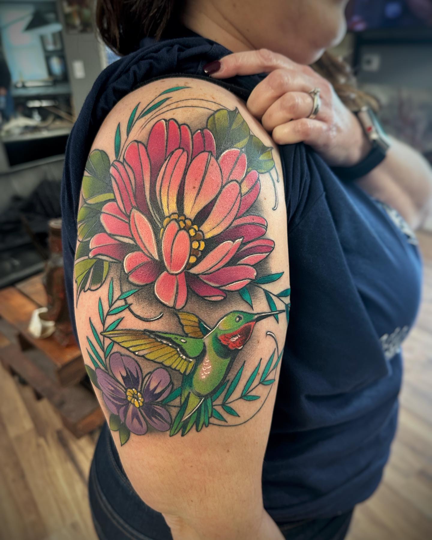 Flower and hummingbird new school tattoo on the upper arm by Derek Hutchison, Des Moines, Iowa