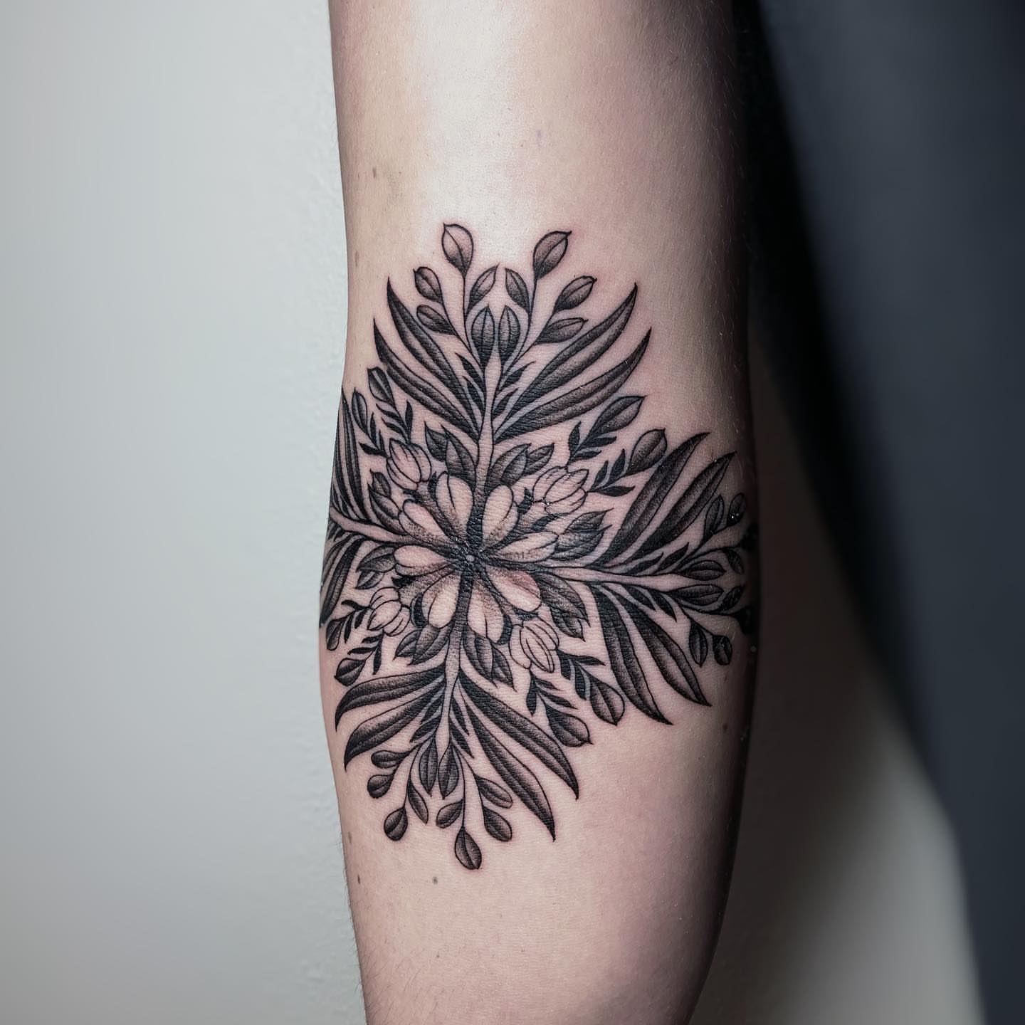 Floral arrangement black and grey tattoo on the forearm by Kolby