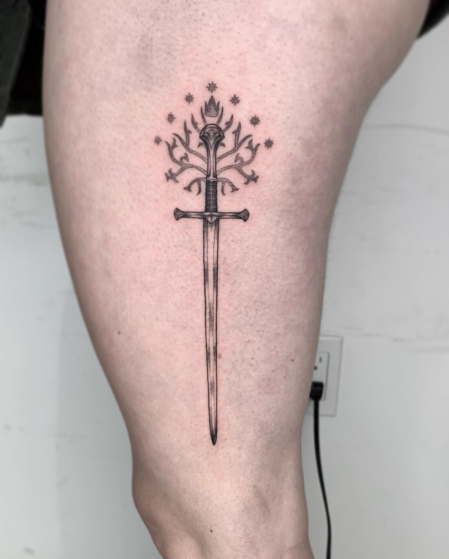 Sword with flame black and grey tattoo on the thigh by Mike G.