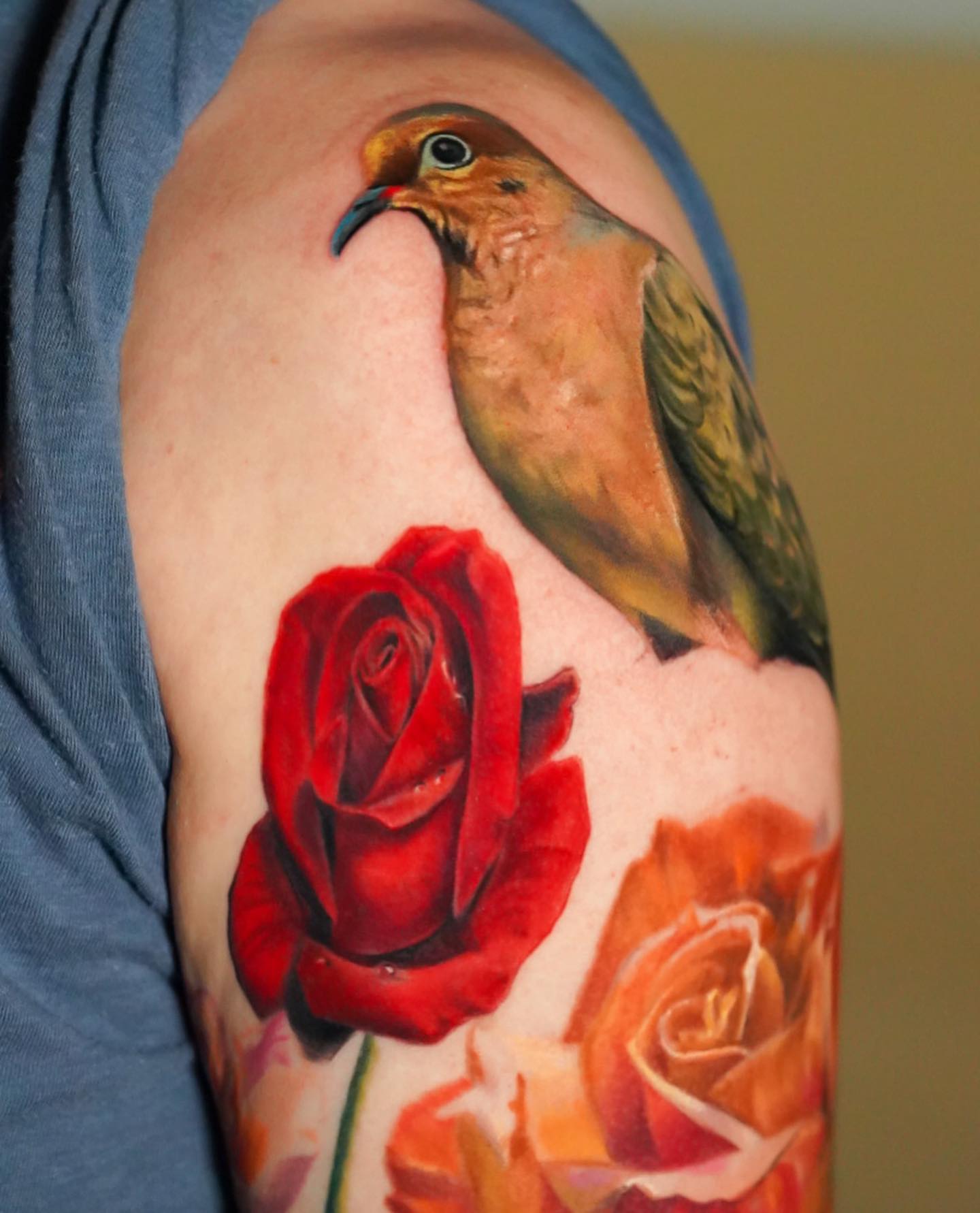 Bird and roses realism tattoo on the upper arm by David Gordon