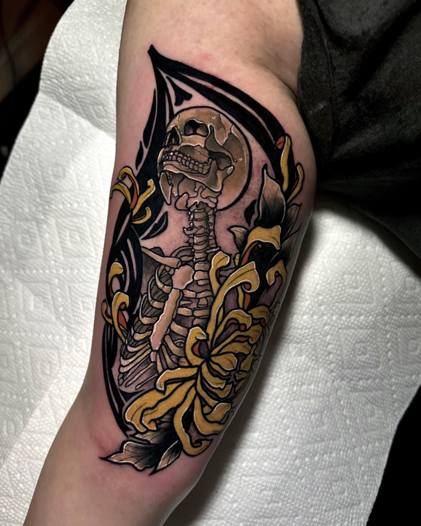 Skeleton with floral elements American traditional tattoo on the forearm by Naysla Droguett
