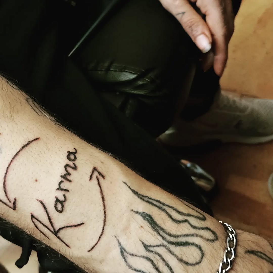 Karma text with arrows tattoo on the forearm by Tatuadora & Piercer