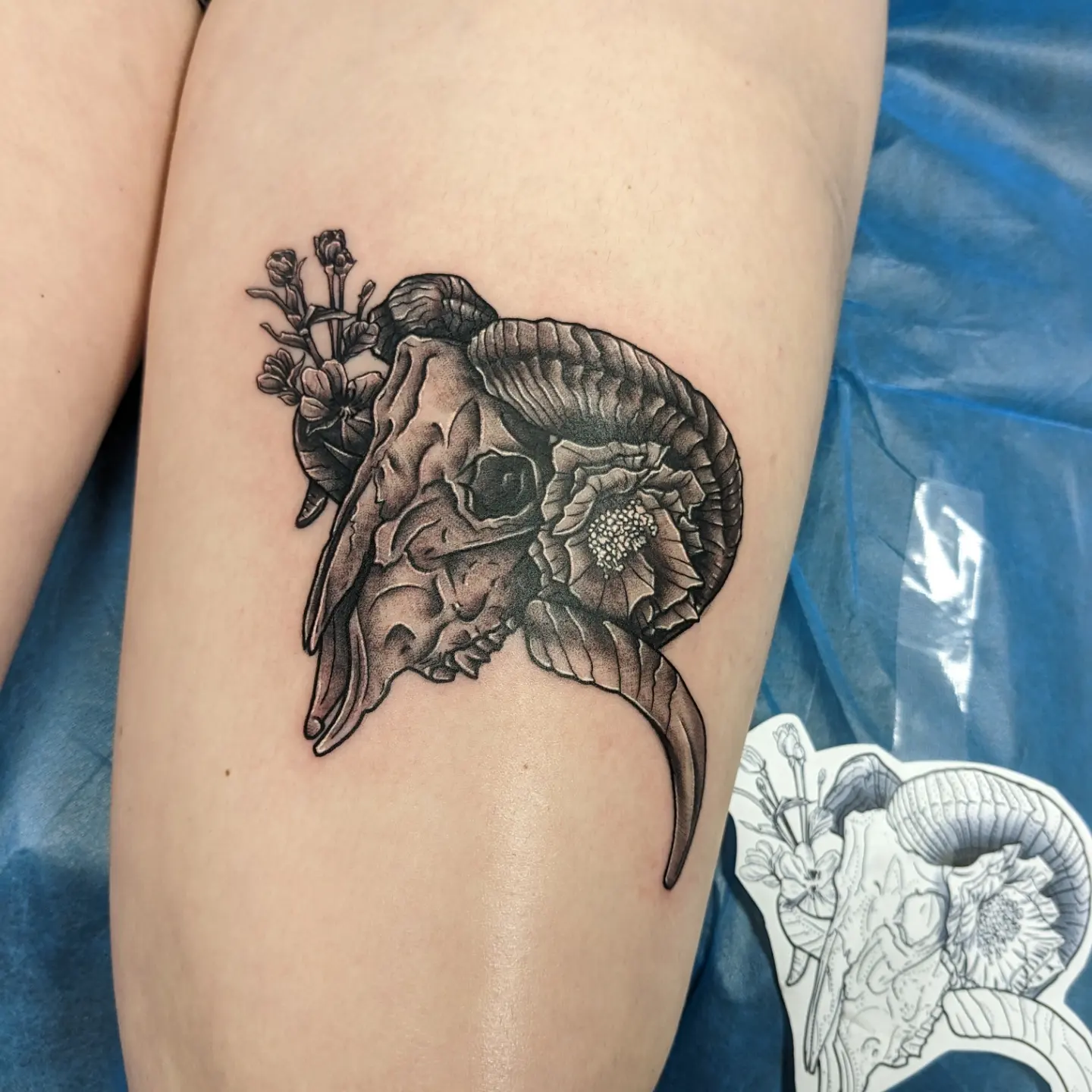 Ram skull with flowers realism tattoo on the thigh by Kara Falcon