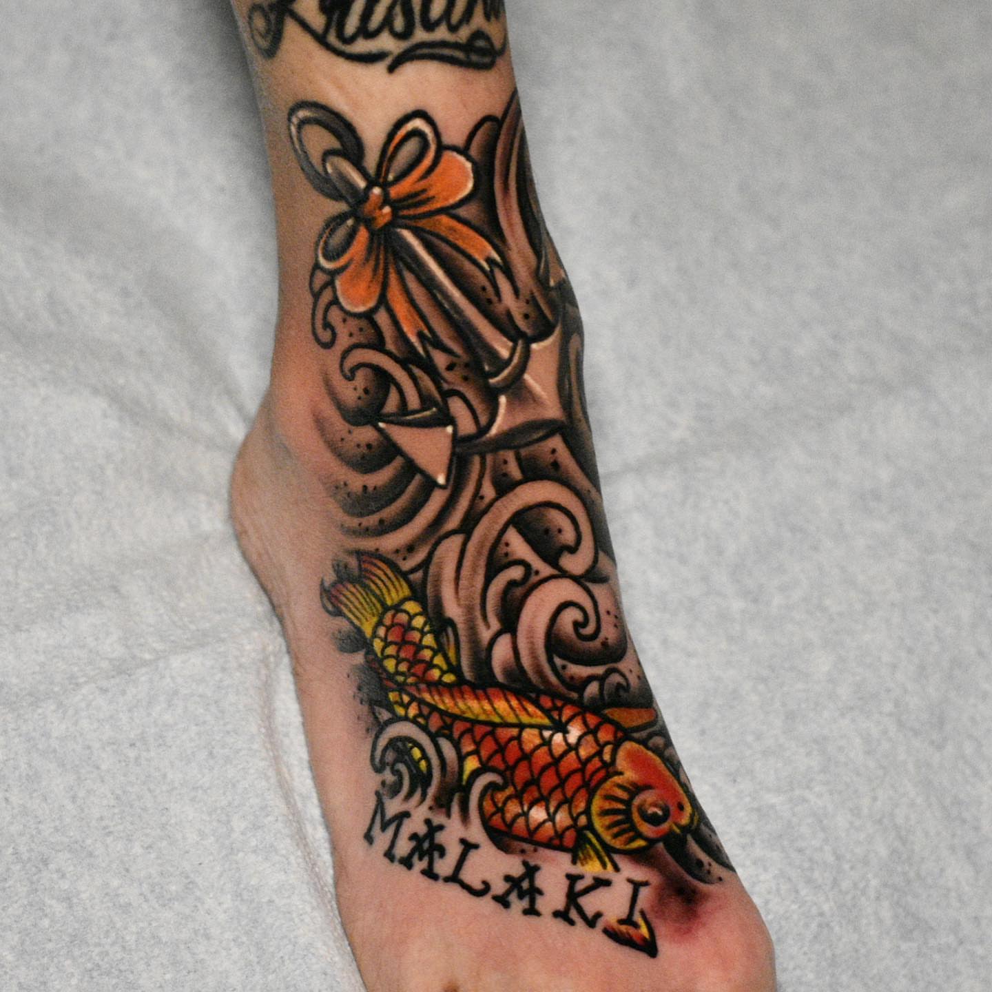 Koi fish and flower American traditional tattoo on the forearm by Raul Ortiz