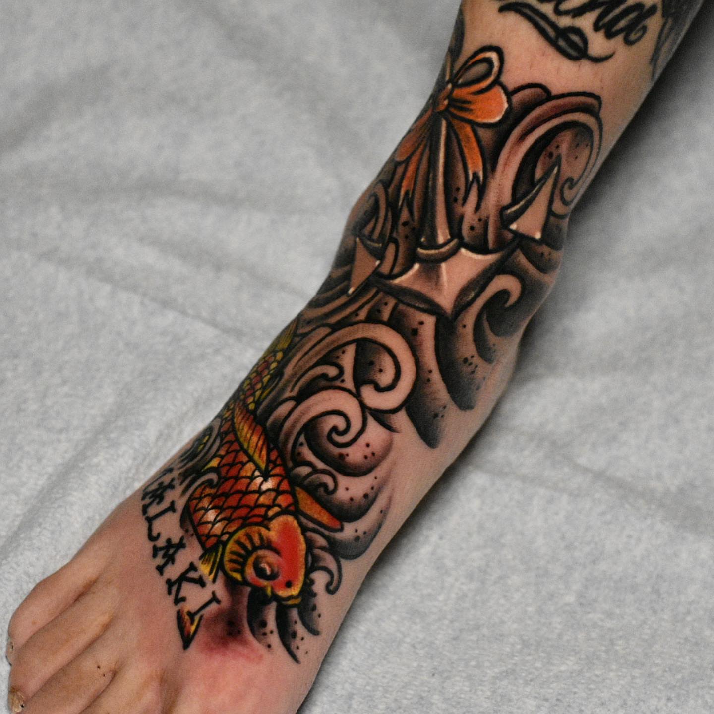 Koi fish American traditional tattoo on the forearm by Raul Ortiz