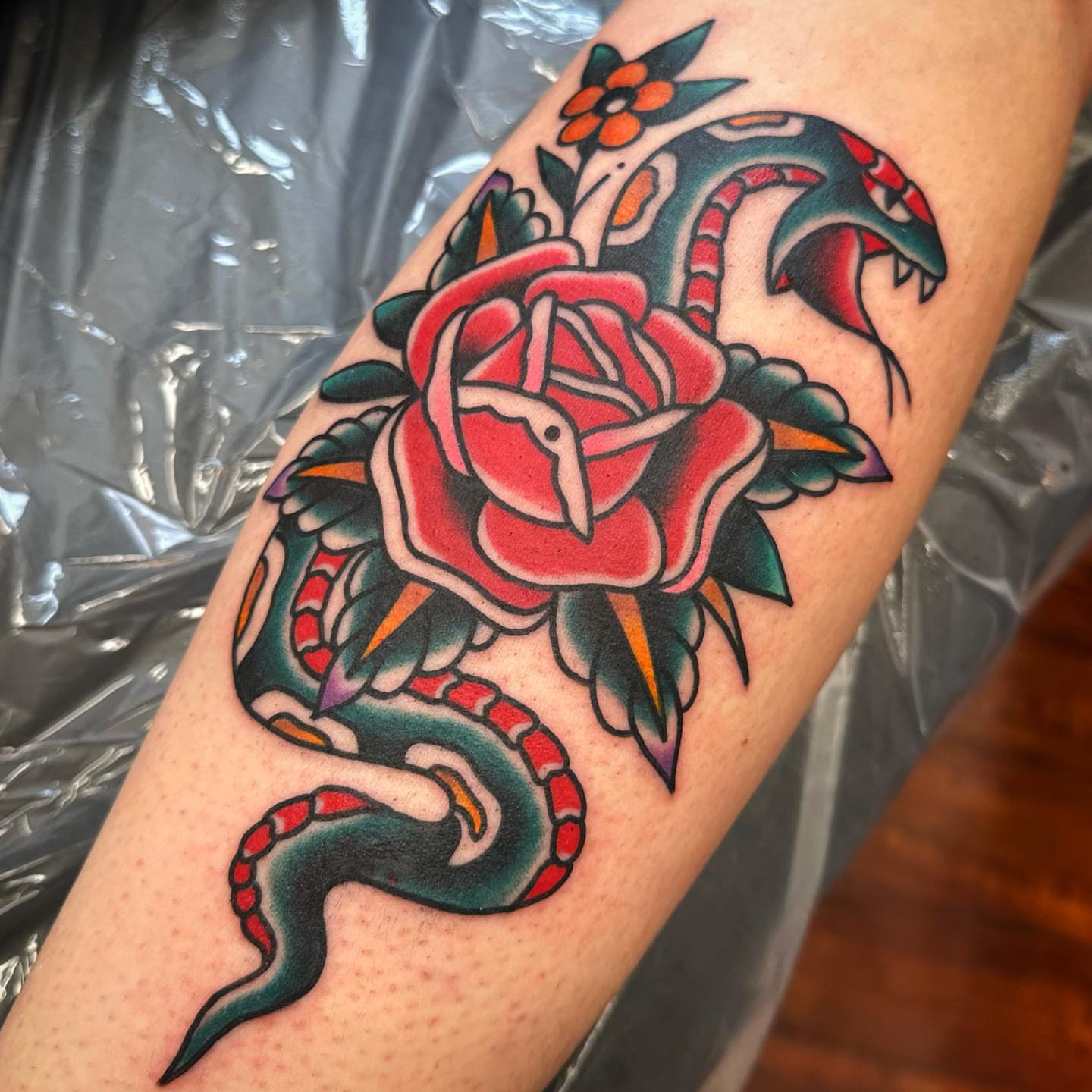 Snake and rose American traditional tattoo on the forearm by Rogelio Robles