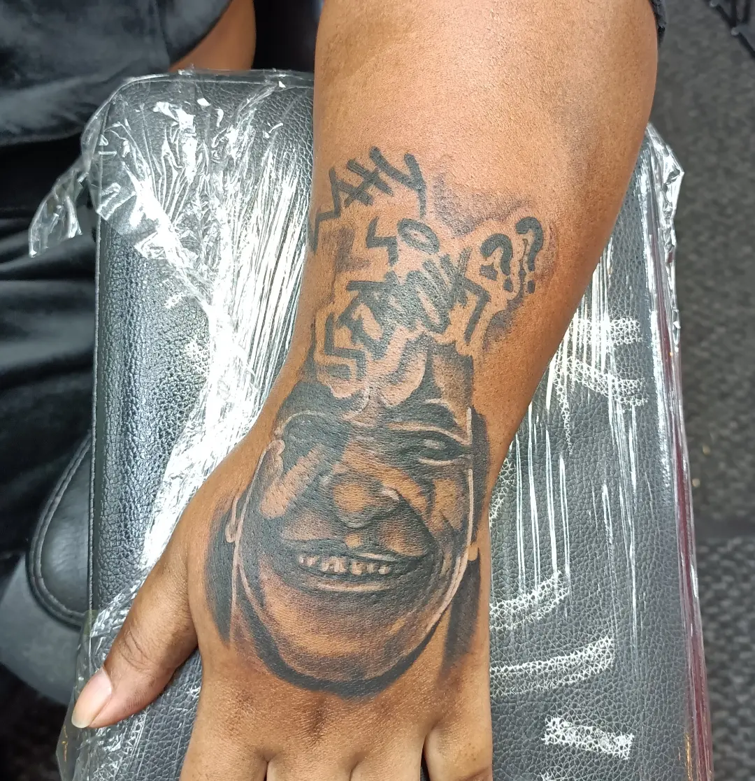 Smiling face black and grey tattoo on the forearm by Daniel Illachek