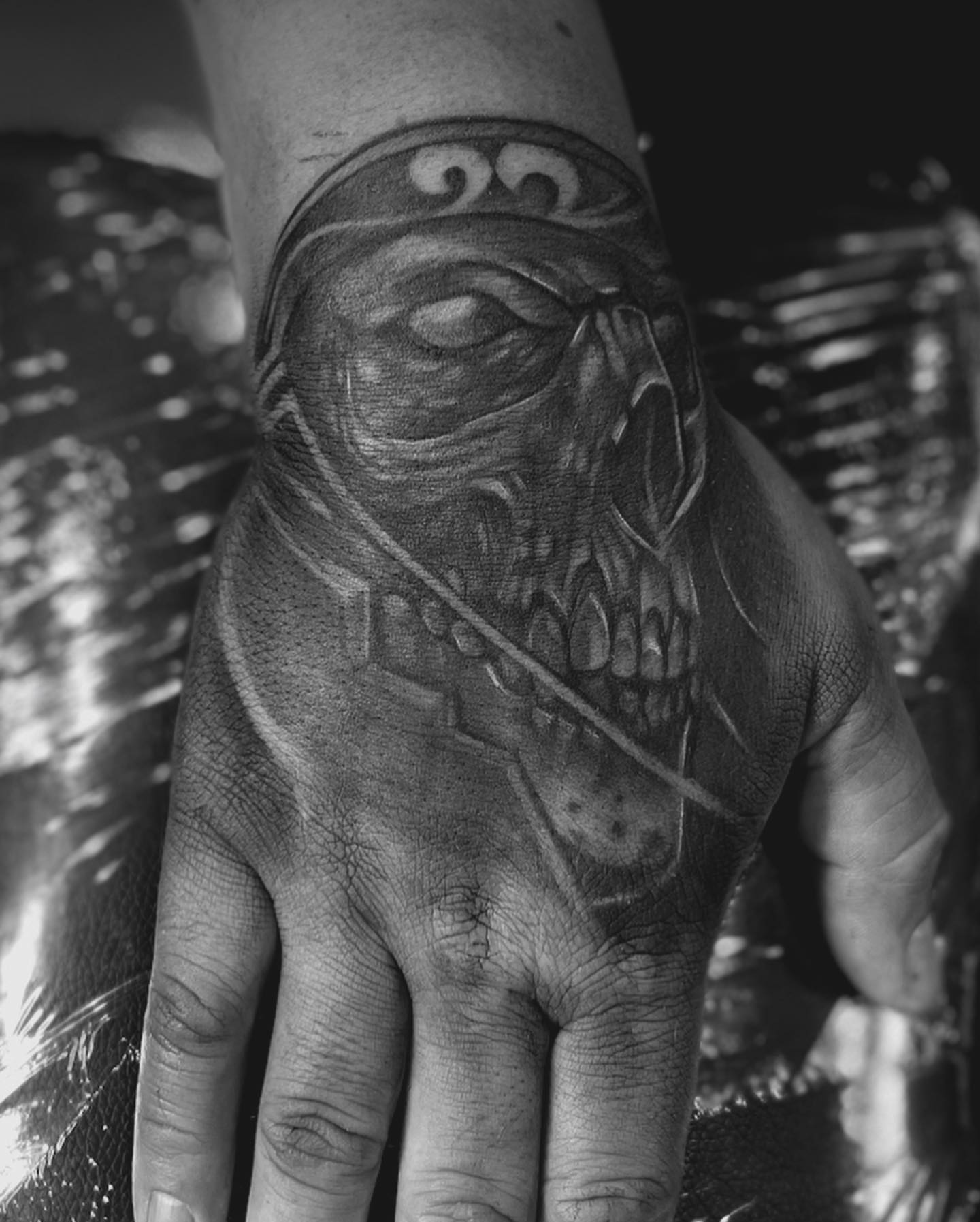 Skull with bandana realism tattoo on the hand by Anwon Johnson