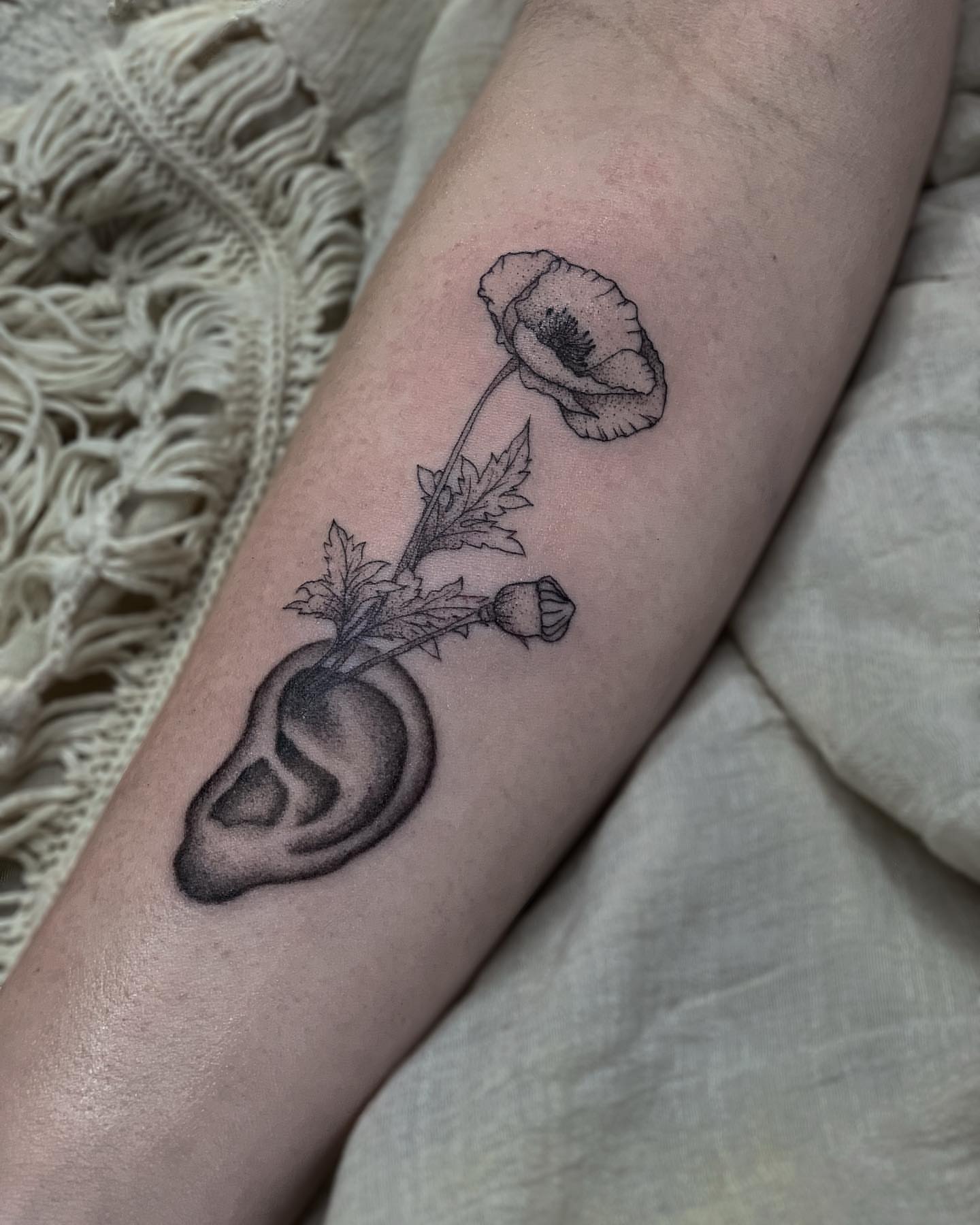 Ear with poppy black and grey tattoo on the forearm by Liv