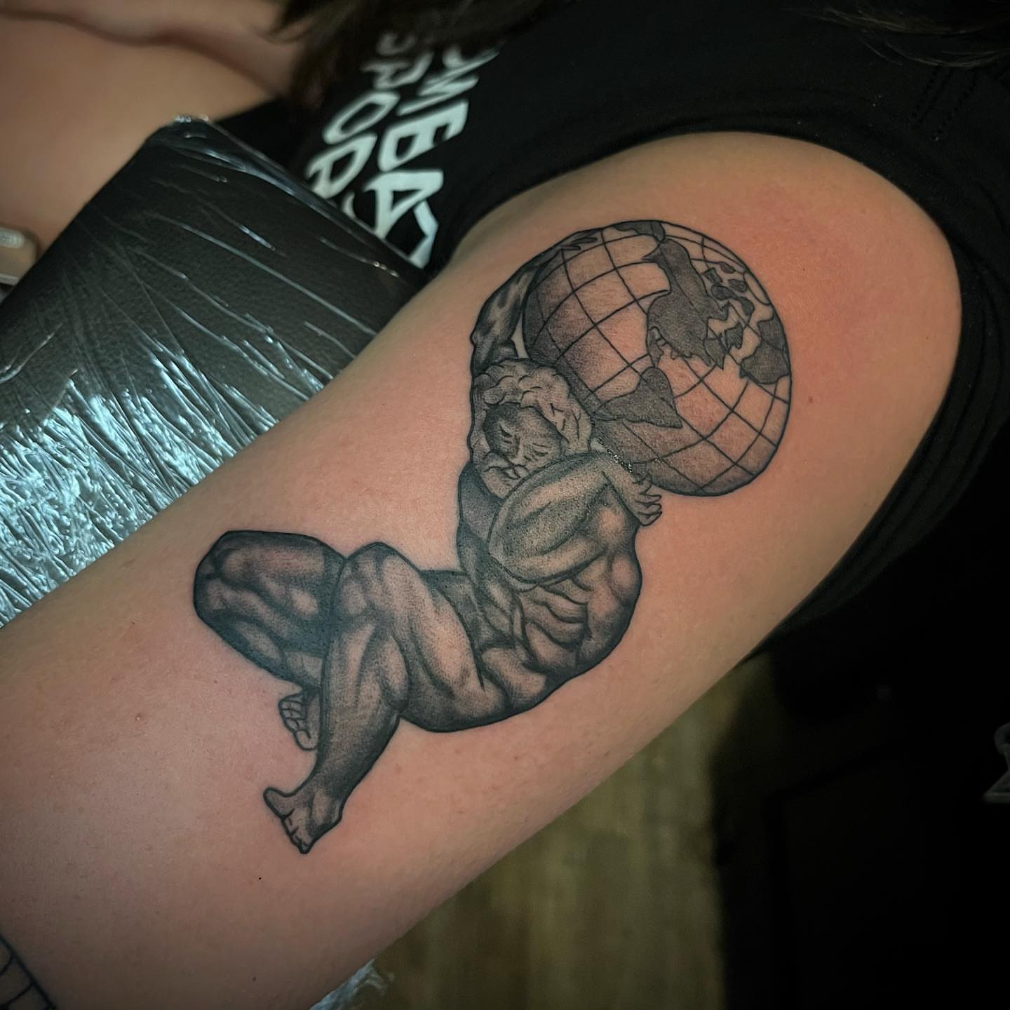Man carrying globe black and grey tattoo on the upper arm by Christopher McGlone