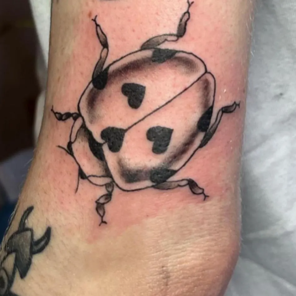 Ladybug black and grey tattoo on the forearm by call (504)441-9275 for info