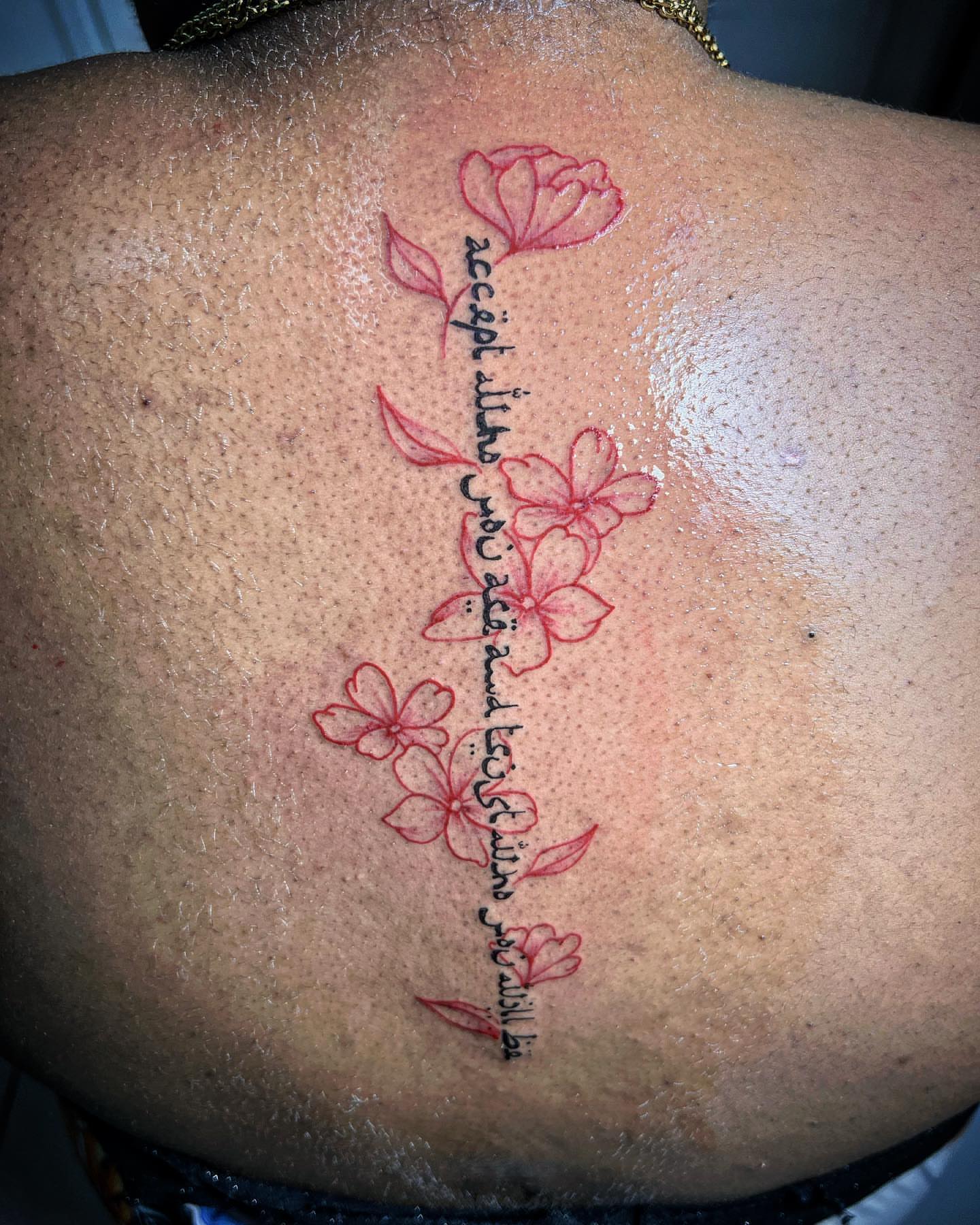 Flowers and Arabic script fine line tattoo on the back by oxideTattoo, Morne-à-l'Eau