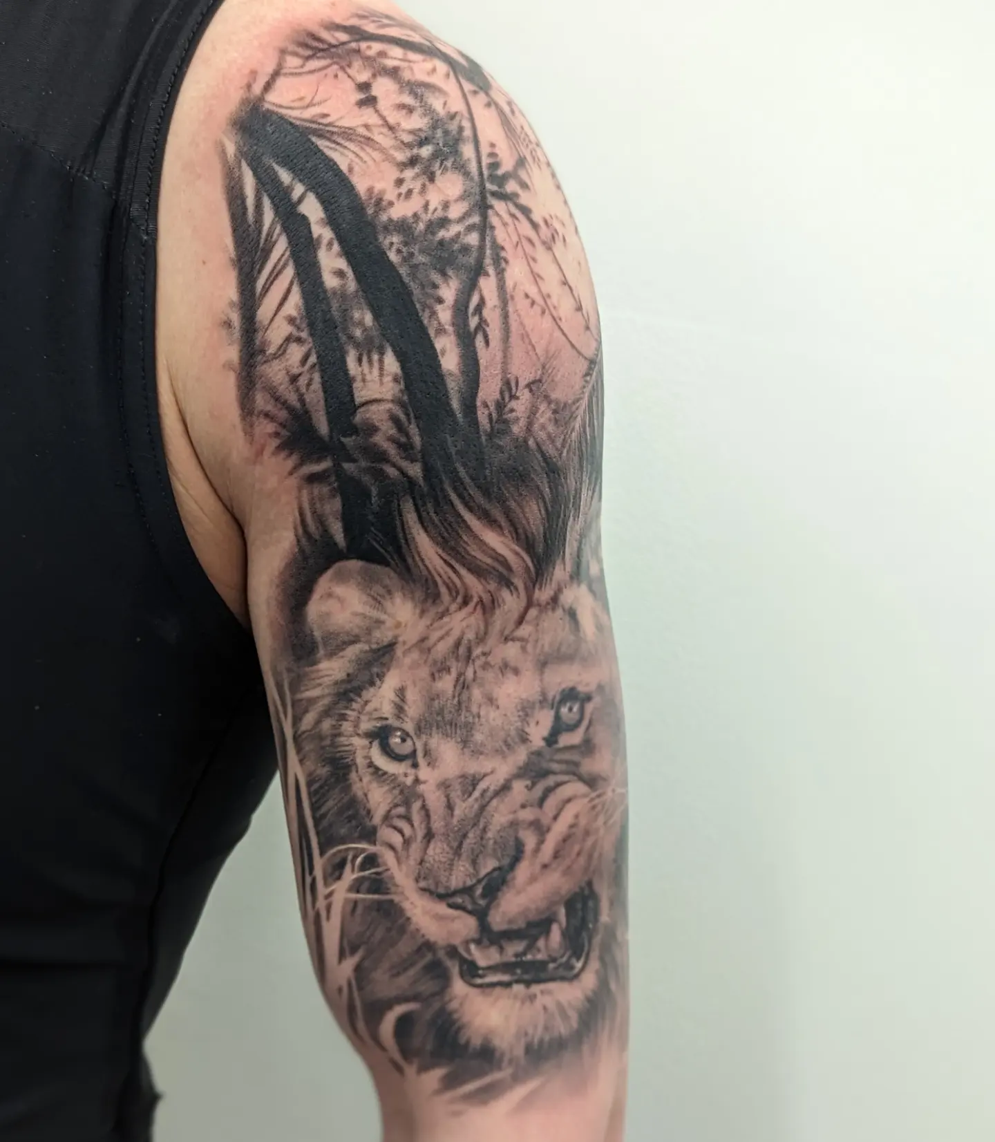 Lion realism tattoo on the upper arm by Sean Costello