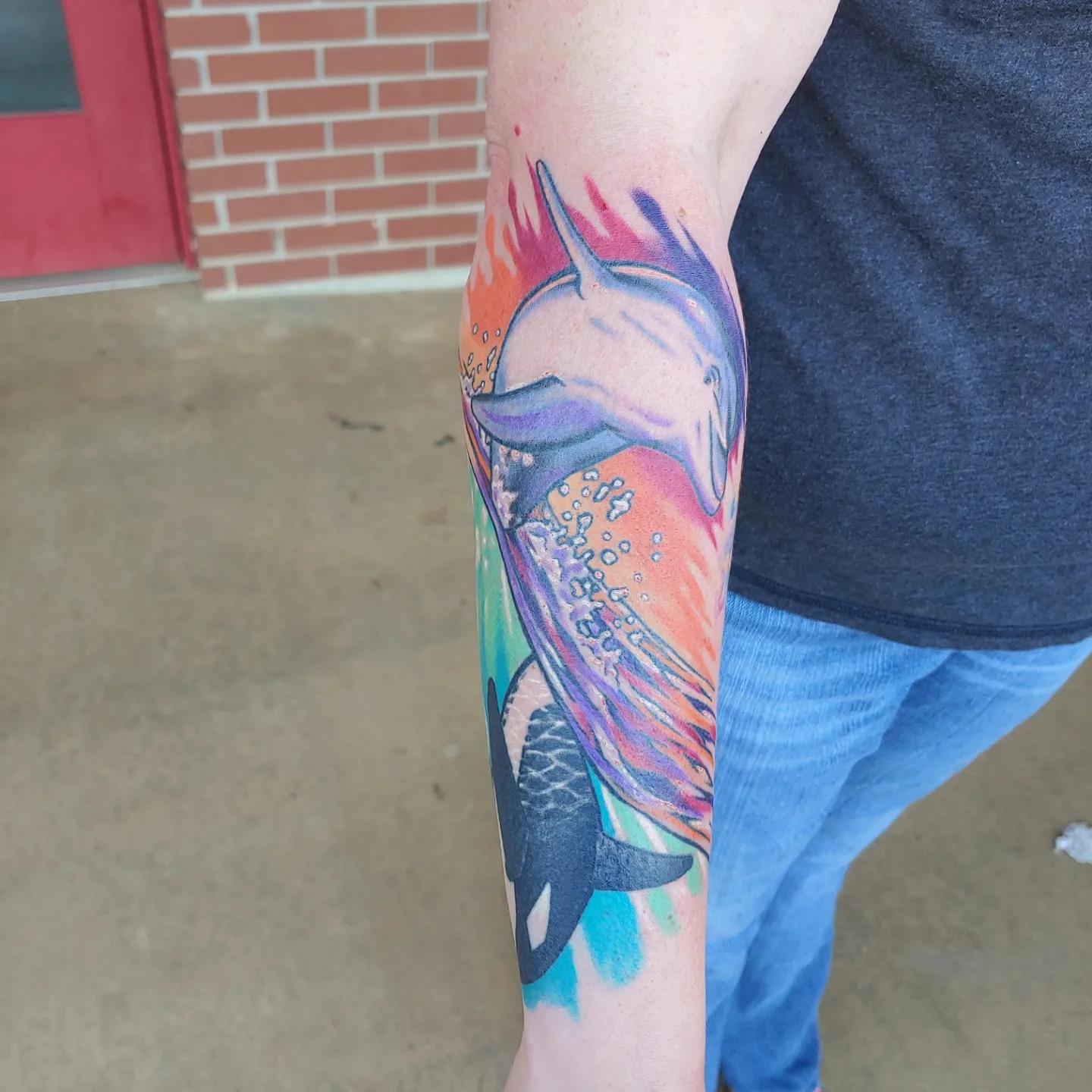 Dolphin and whale new school tattoo on the forearm by Gene Britton