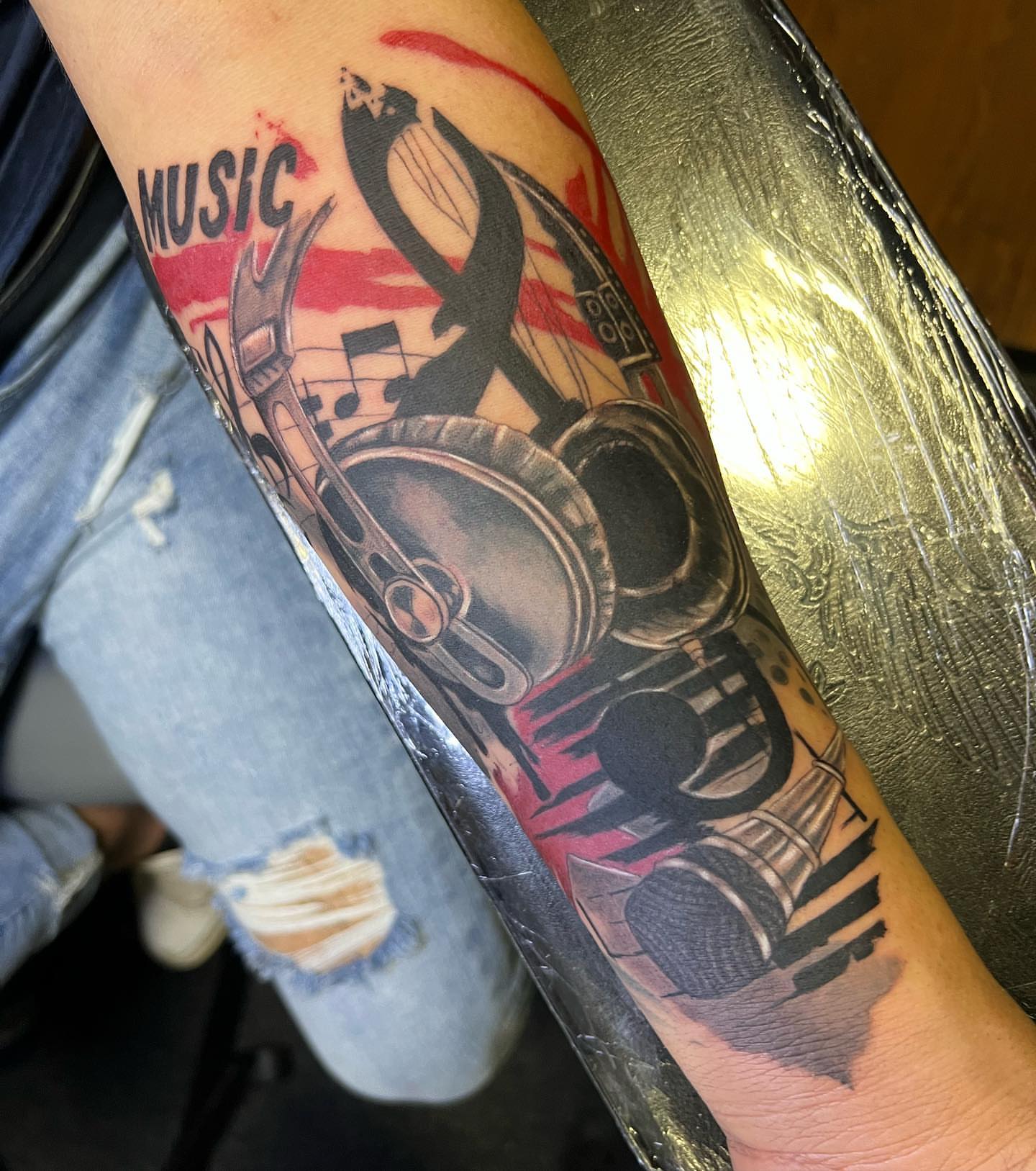 Music-themed realism tattoo on the forearm by JT Ink