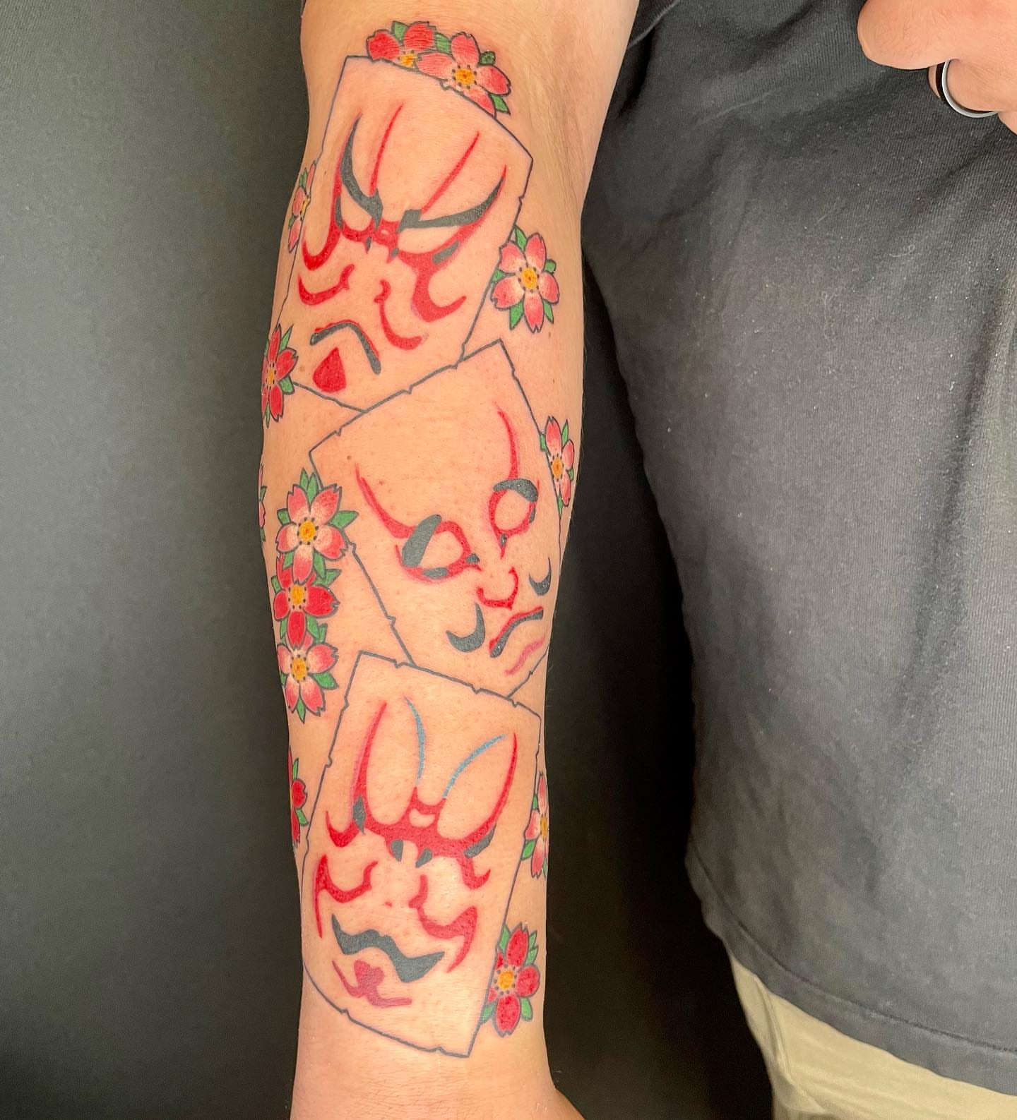Masked faces American traditional tattoo on the forearm by Seth Griffin