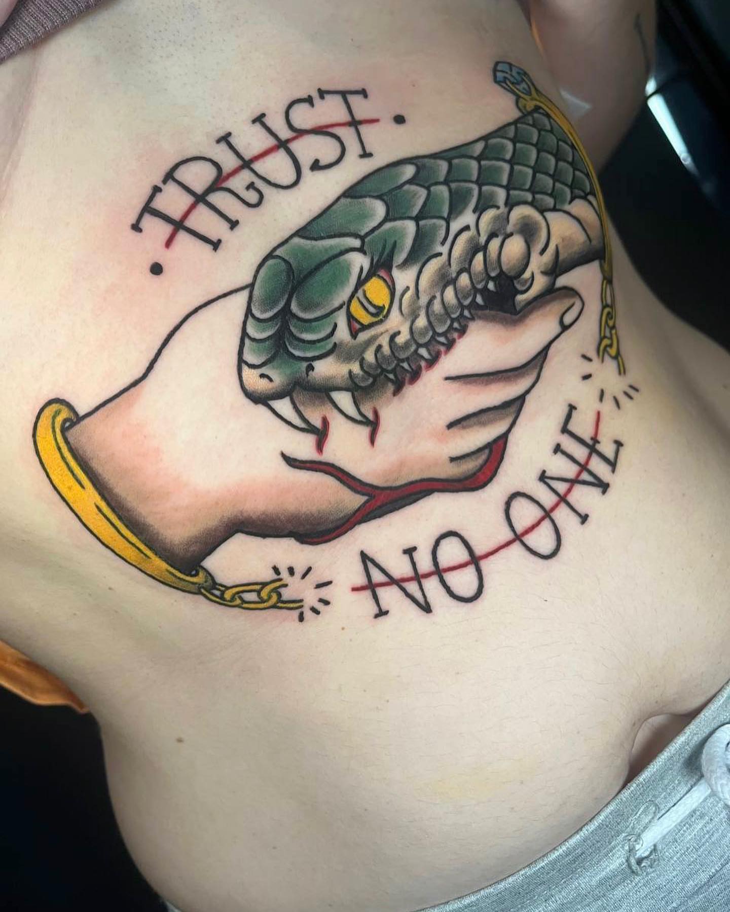 Snake biting hand American traditional tattoo on the chest by Marta La Jirafa