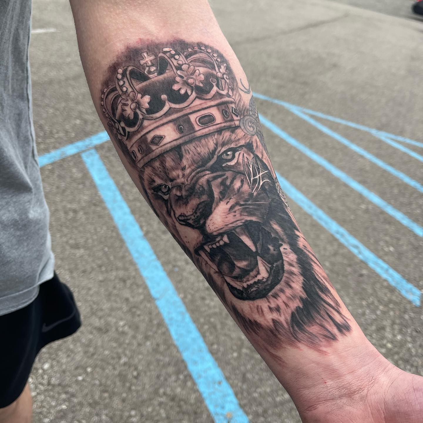 Lion crown realism tattoo on the forearm by Antonio Massimino