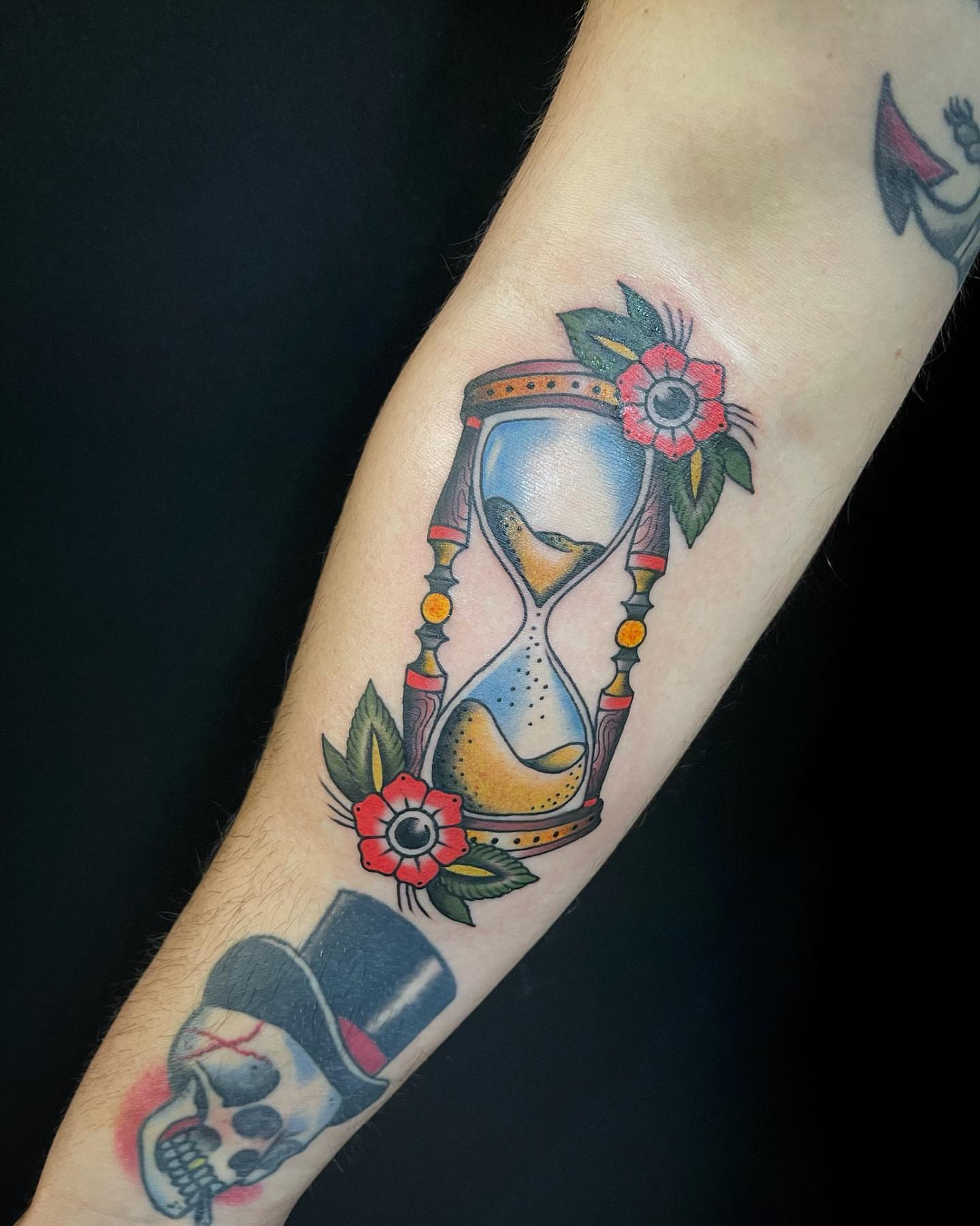 Hourglass with flowers American traditional tattoo on the forearm by Lexx Christine