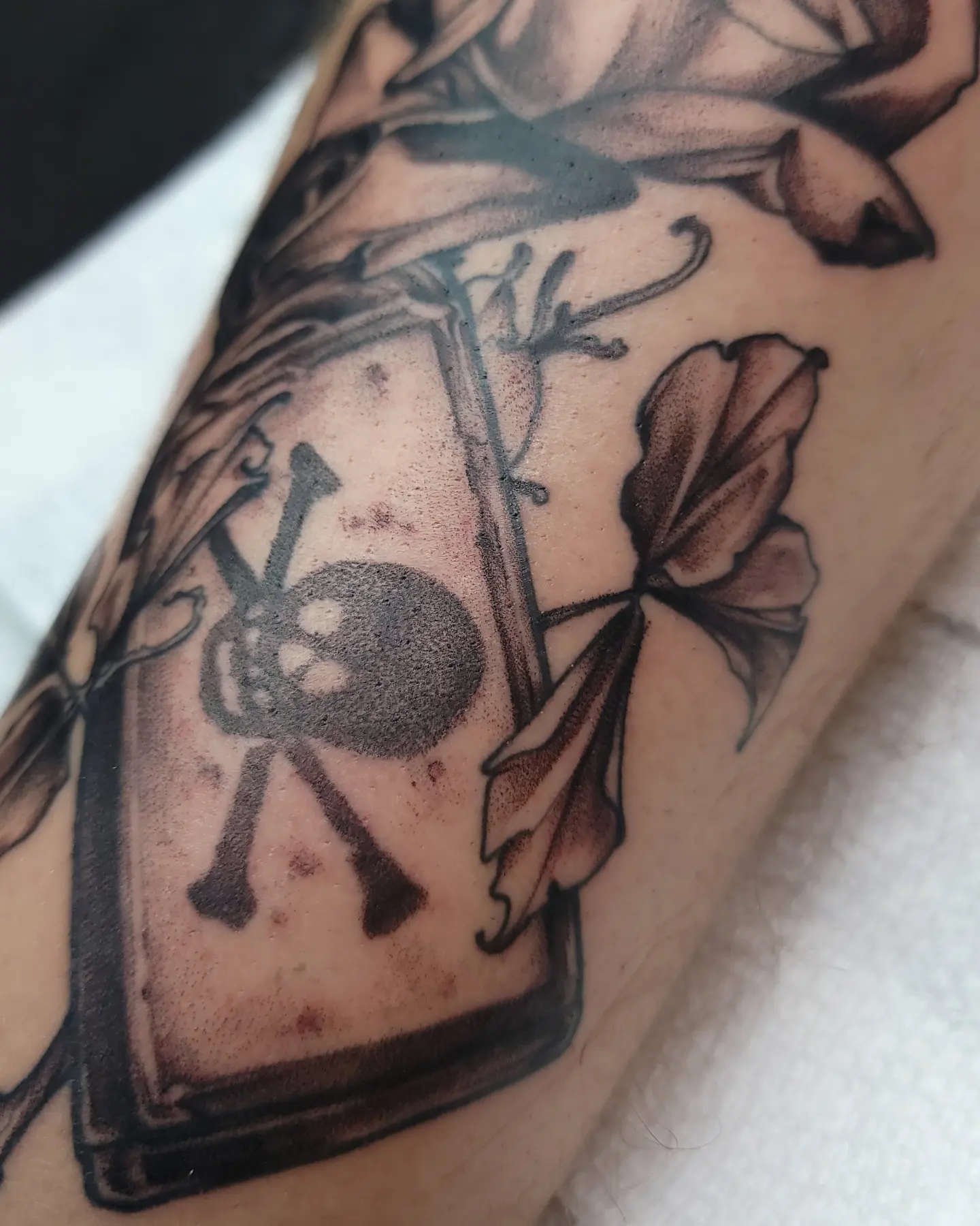 Book with skull and crossbones black and grey tattoo on the forearm by Ghost