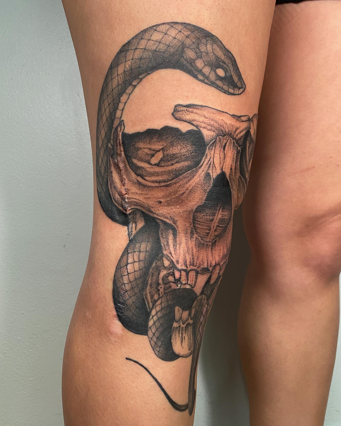 Snake and skull realism tattoo on the thigh by Tattoo Artist