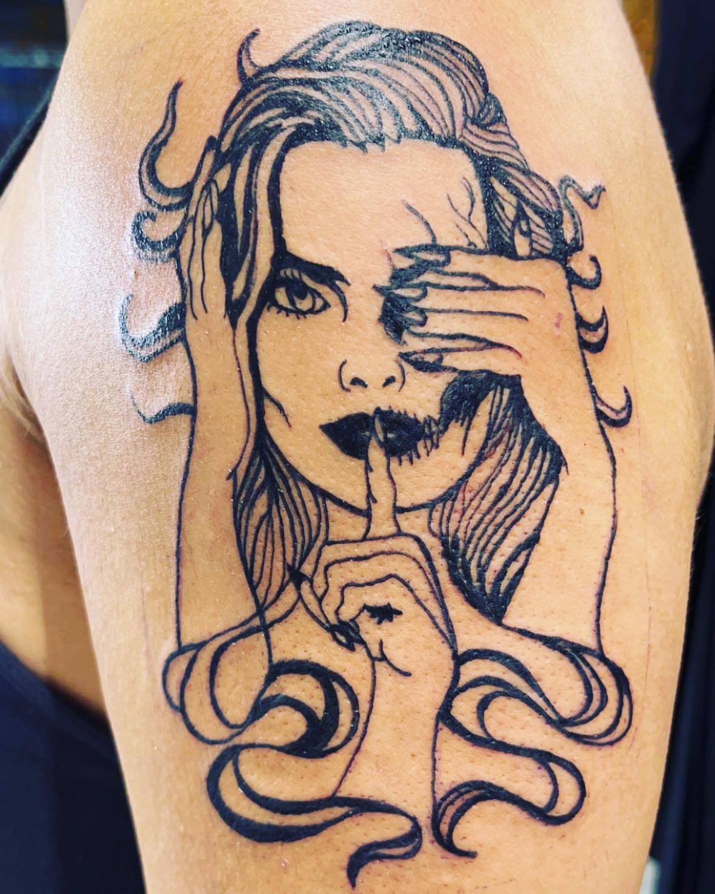 Woman with finger over mouth black and grey tattoo on the upper arm by Frankie Sodapop Plumley