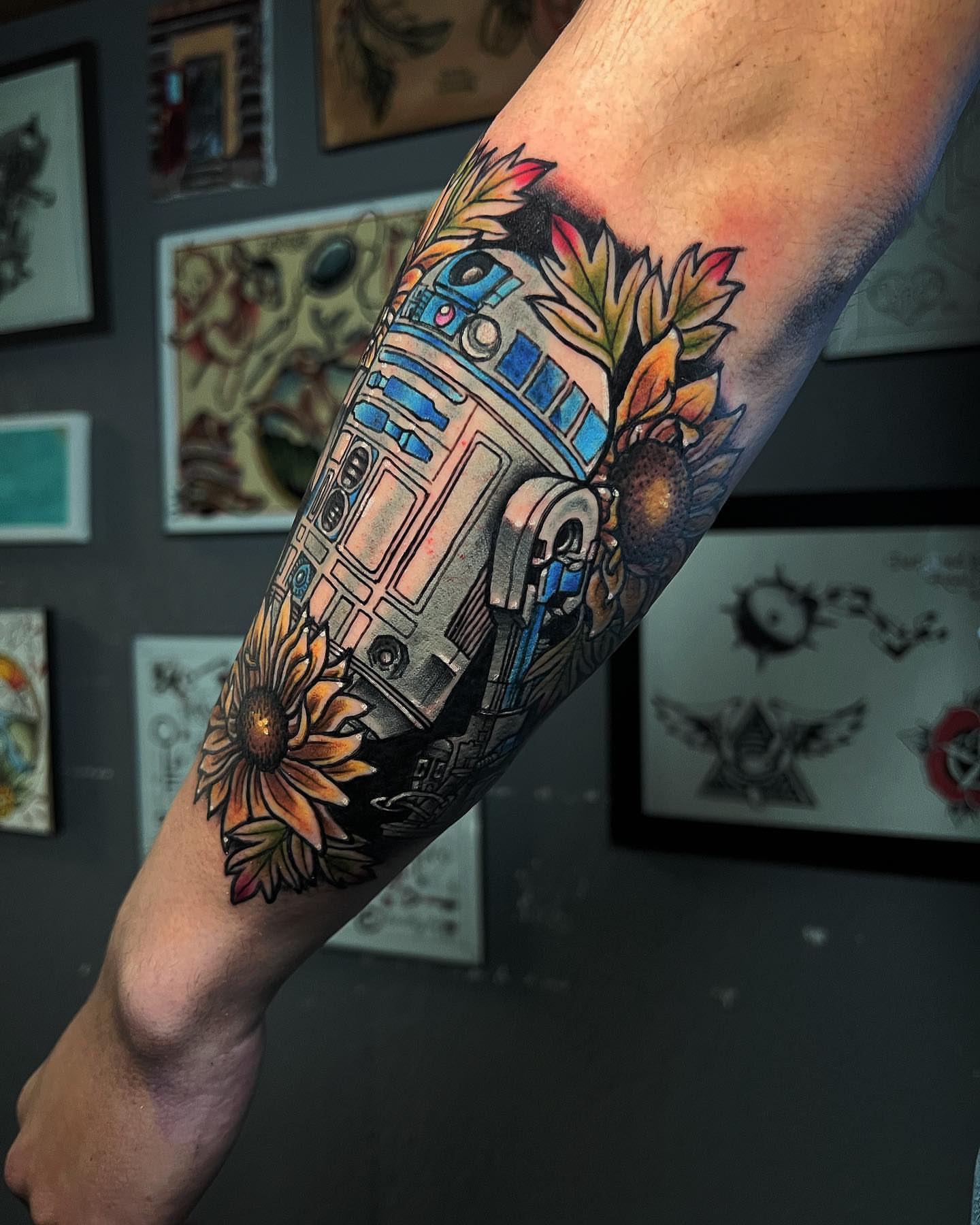 R2-D2 with sunflowers American traditional tattoo on the forearm by Raul Ortiz