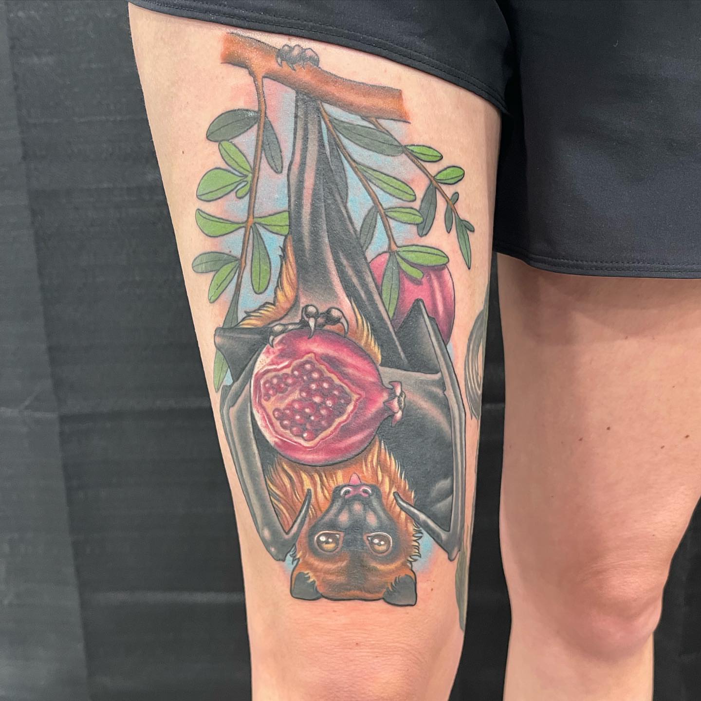 Bat and pomegranate realism tattoo on the thigh by Paul Hicks