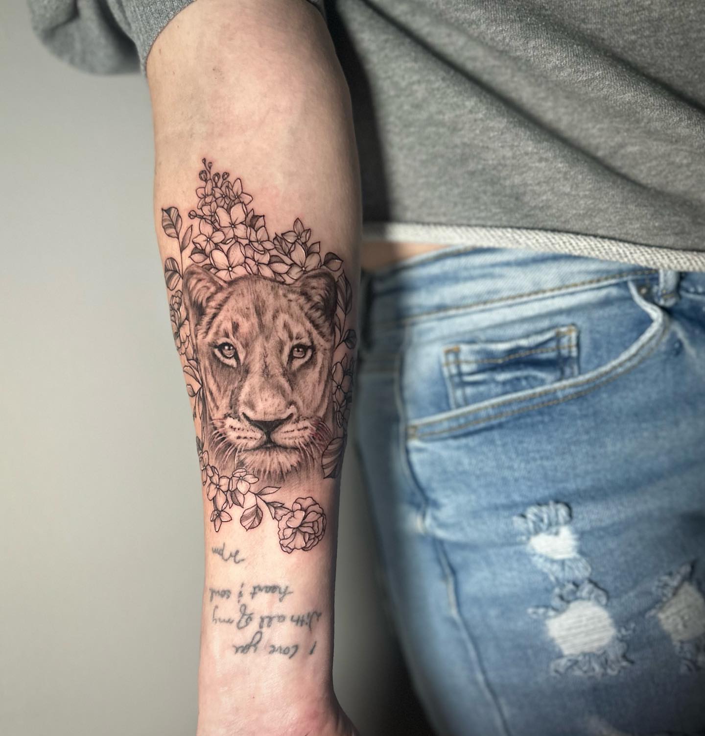 Lion with floral crown realism tattoo on the forearm by Megan McKee Tattoo Artist