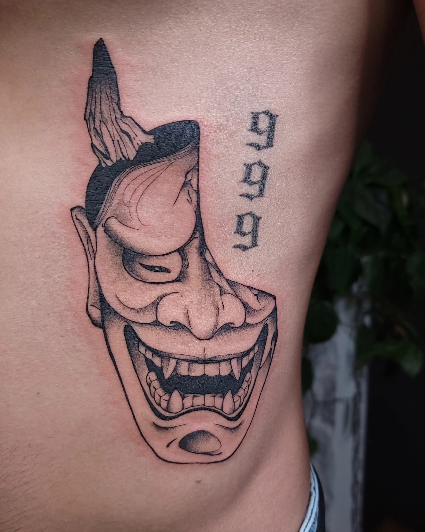 Demon mask black and grey tattoo on the thigh by Ghost
