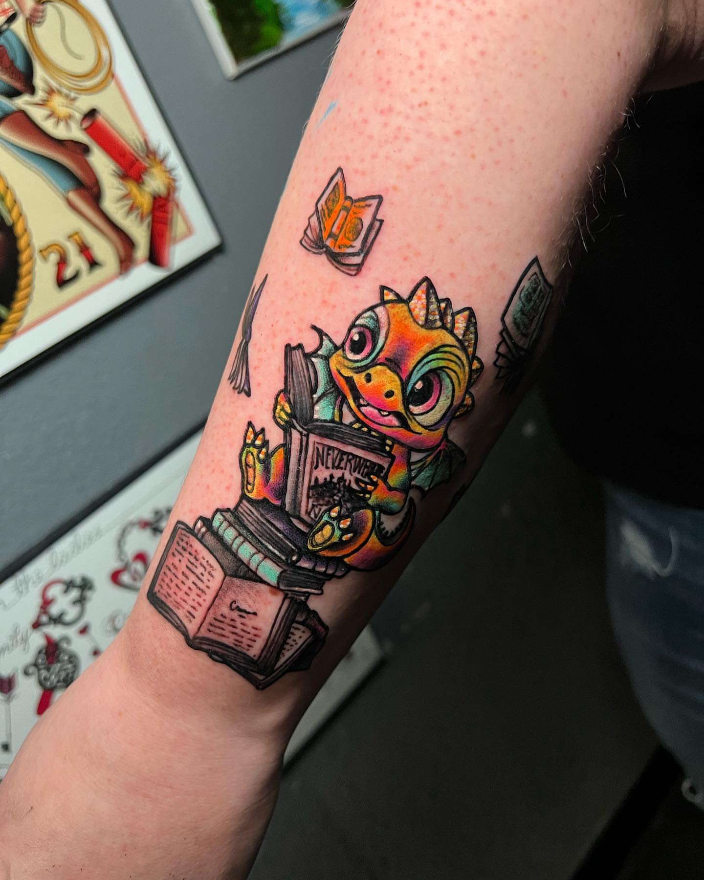 Dragon reading new school tattoo on the forearm by Raul Ortiz