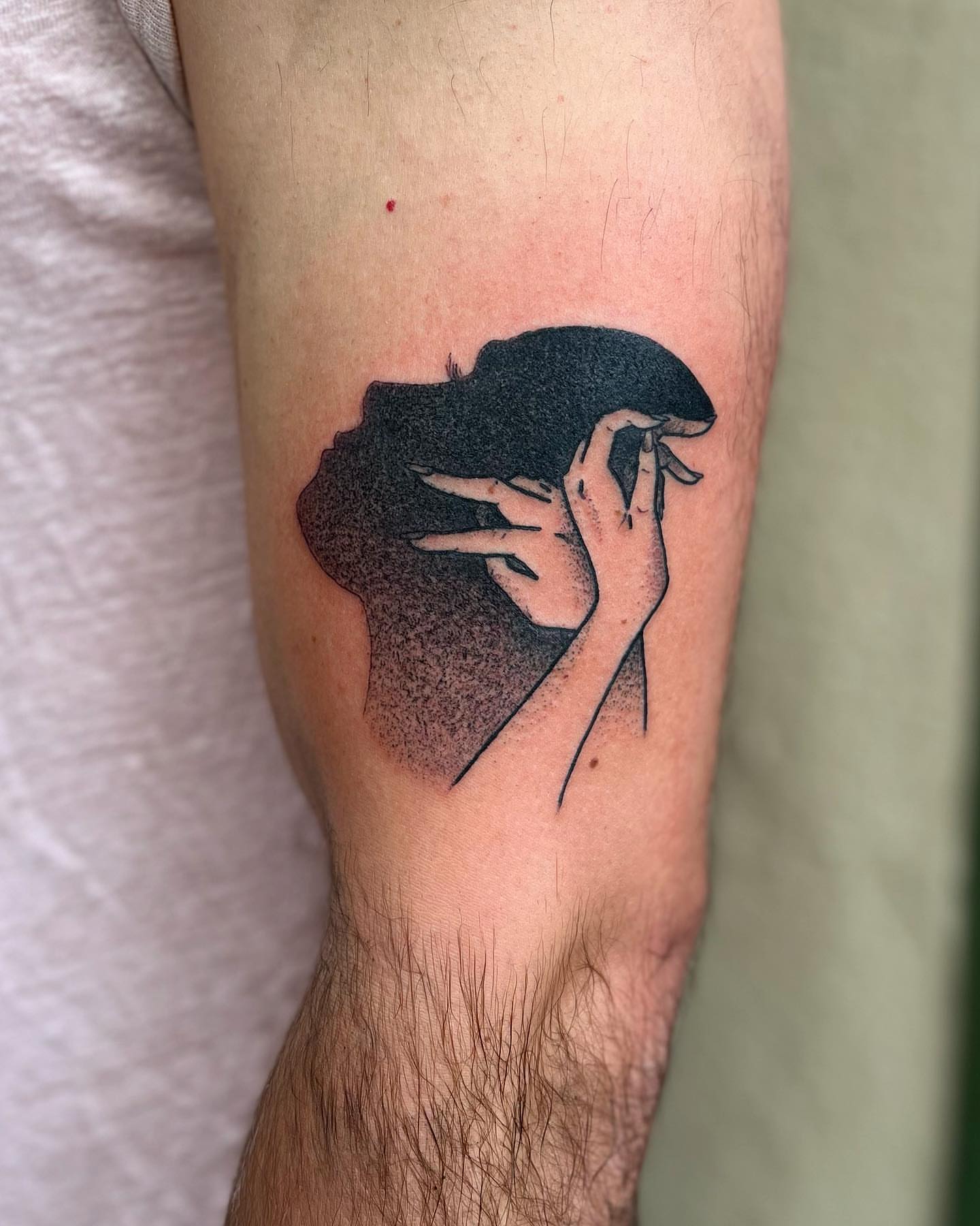 Hand holding phone dotwork tattoo on the forearm by Daniel Patrick