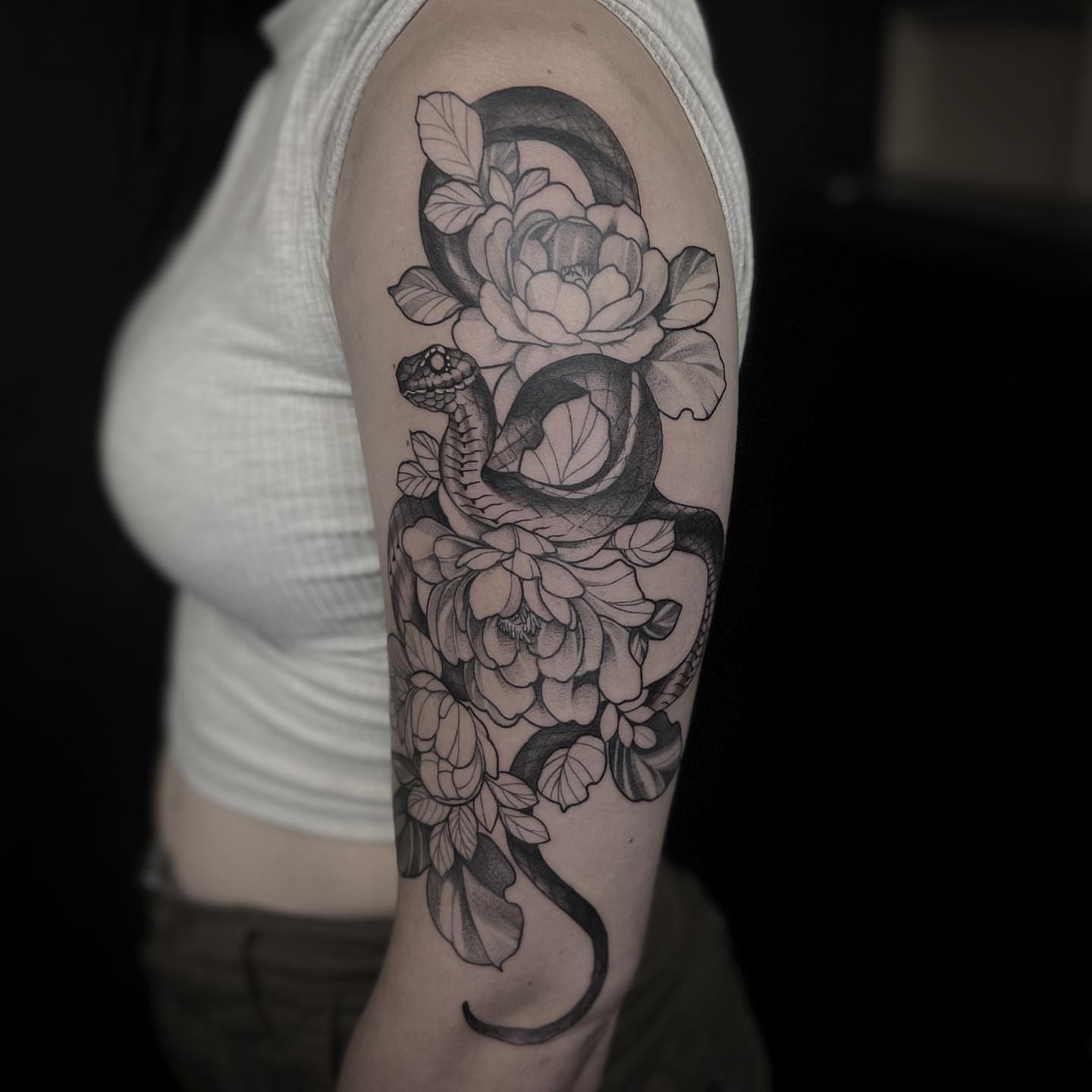 Snake and peony realism tattoo on the upper arm by 𝐓𝐚𝐭𝐭𝐨𝐨 👩🏻‍🎨