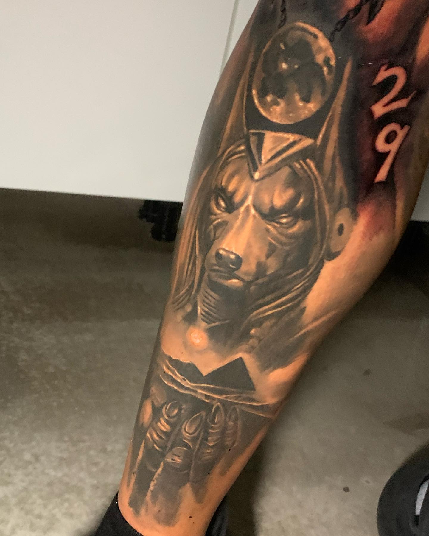 Dog with headdress black and grey tattoo on the forearm by james padelt